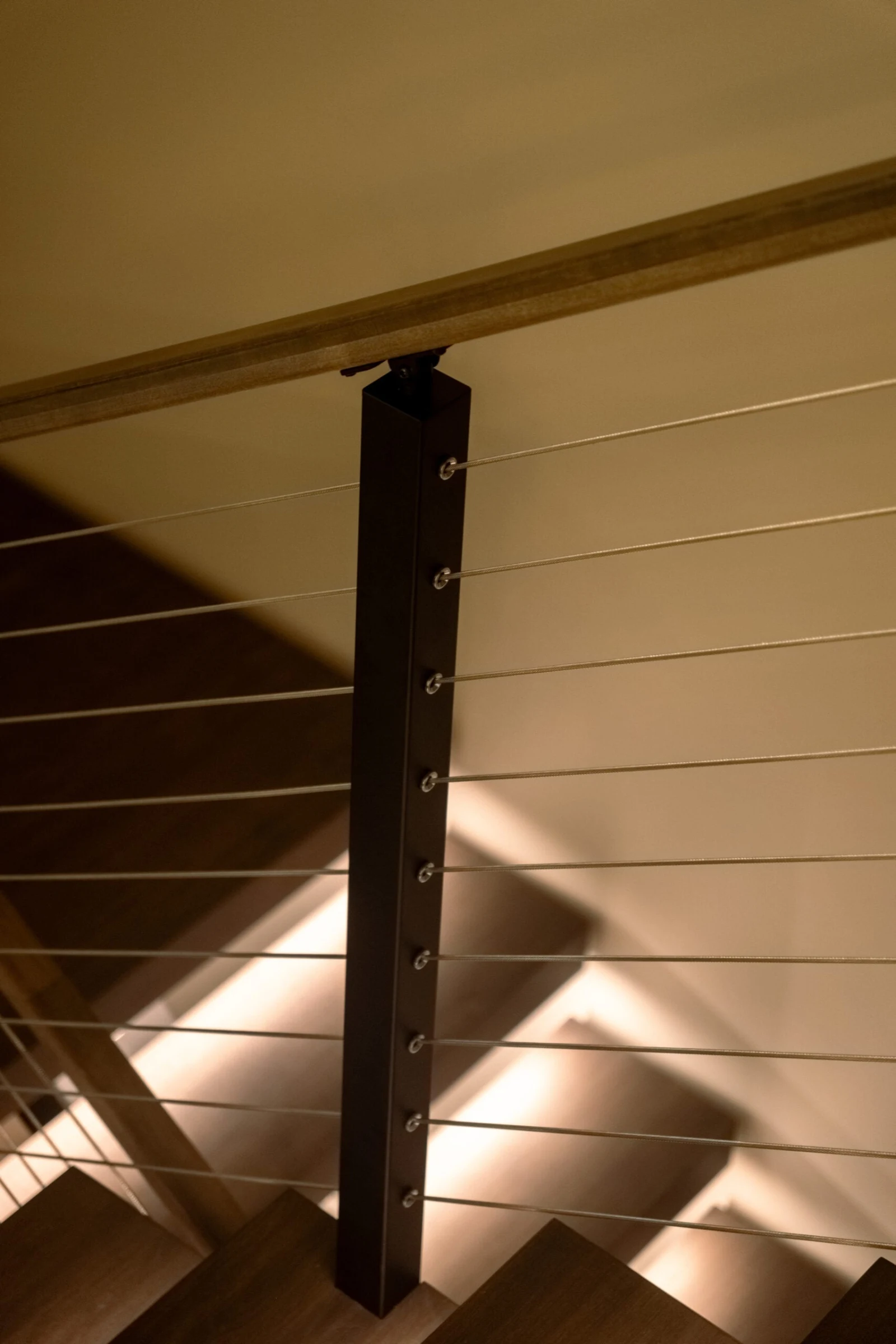 Close view of a black cable railing post with taut stainless cables