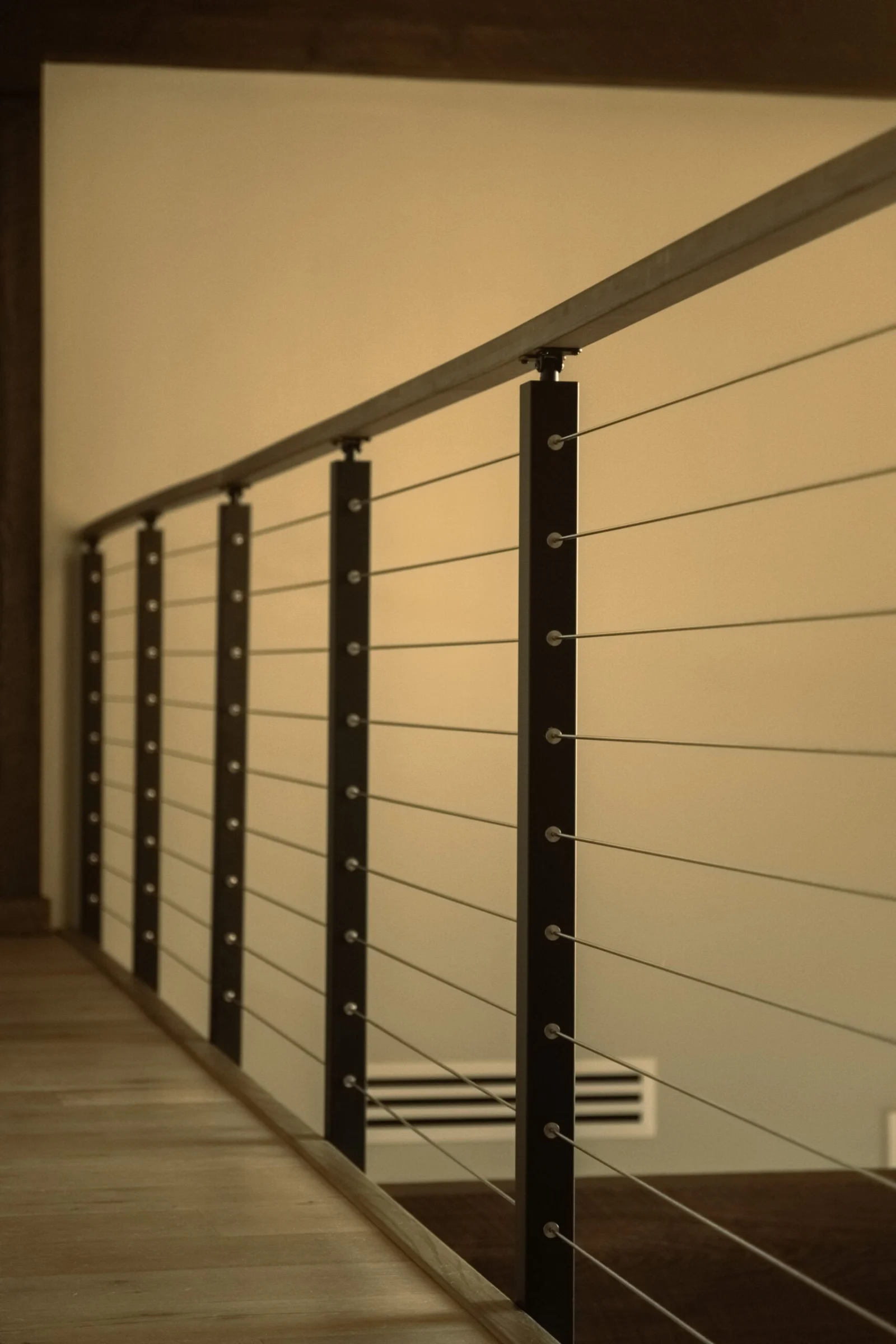Long cable railing run with evenly spaced black posts along an upper hallway