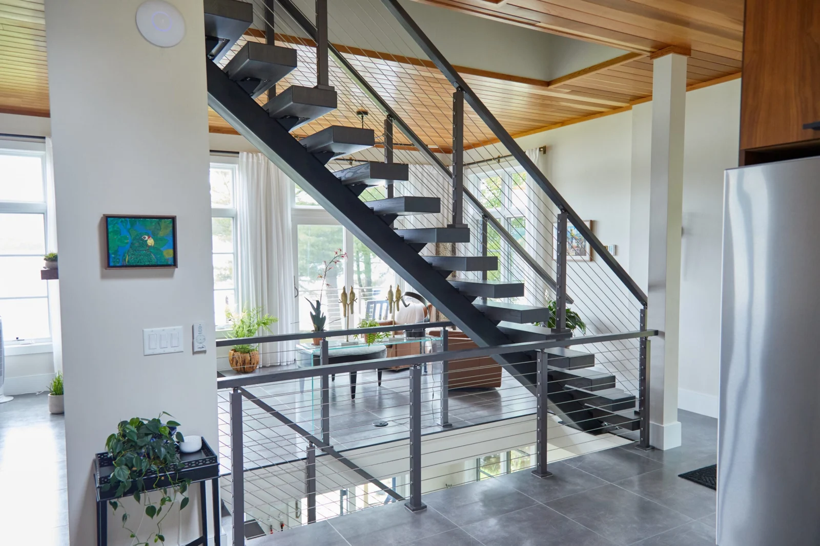 Wide room view of the floating stair beside the kitchen and glass doors