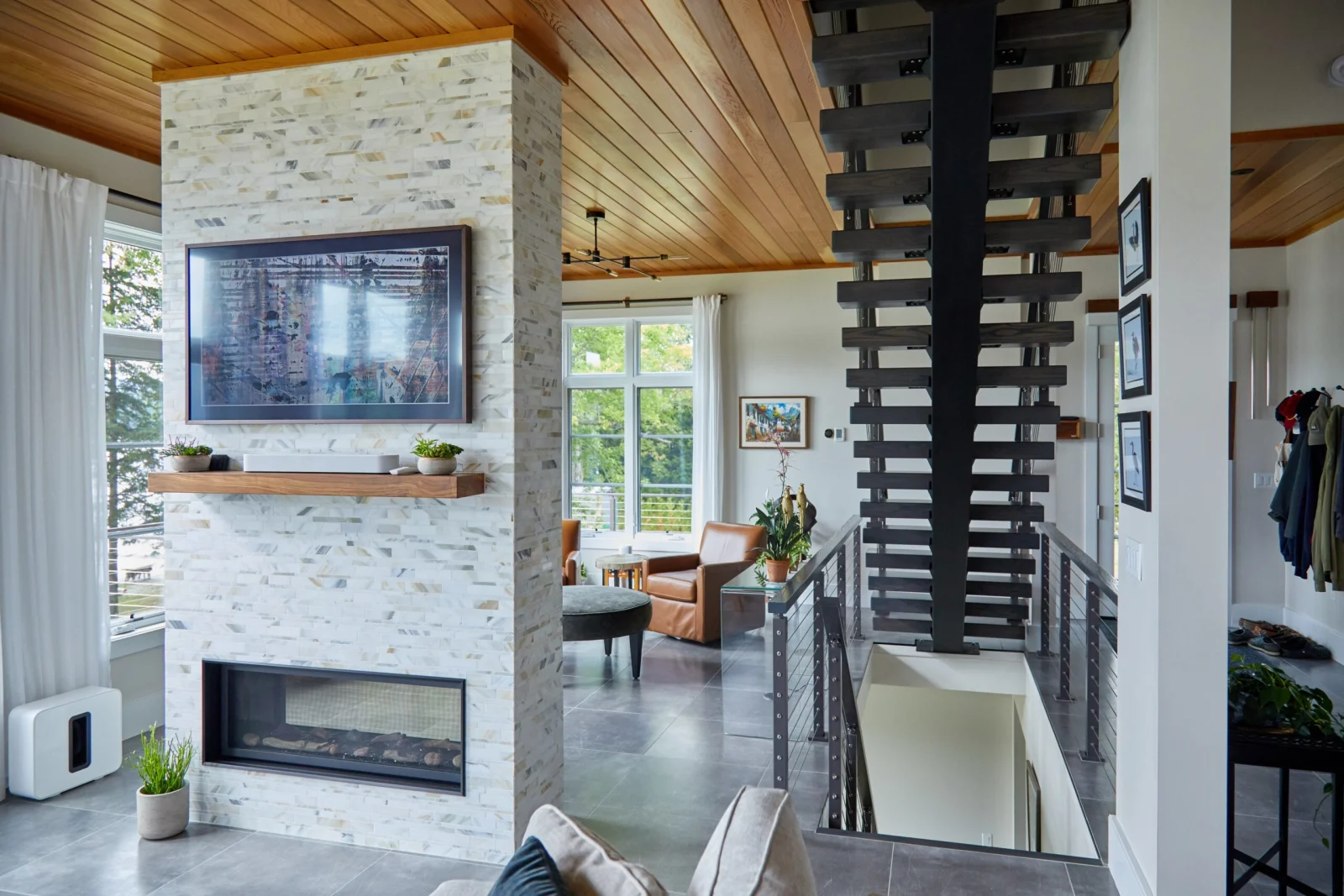 Stair stringer rising past a stone fireplace in an open living space