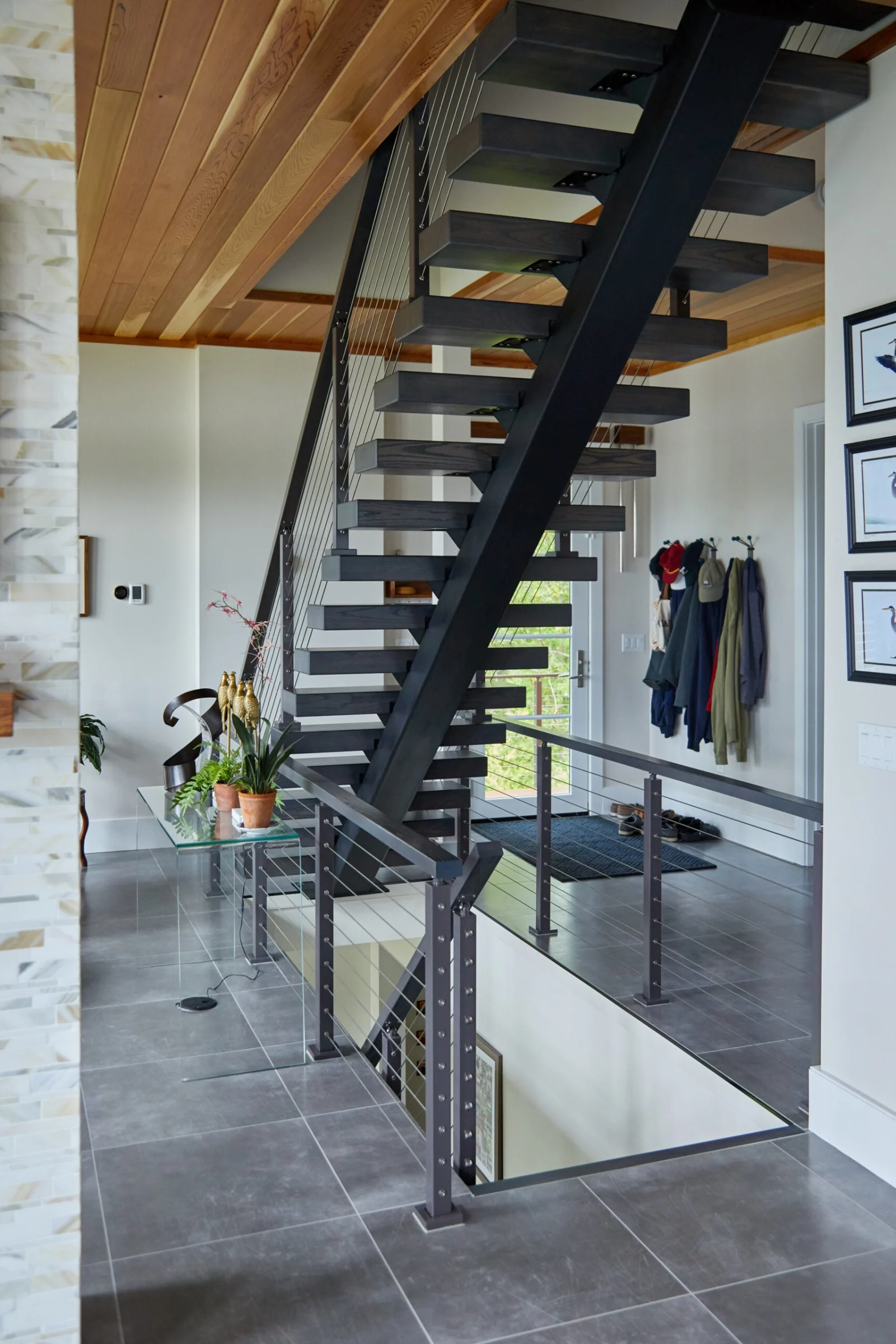 View up the stair flight from a tiled entry under a wood ceiling