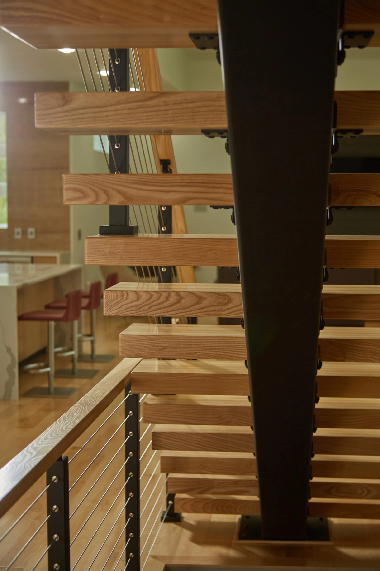 Treads cantilevered from a tapered black stringer above a wood top rail