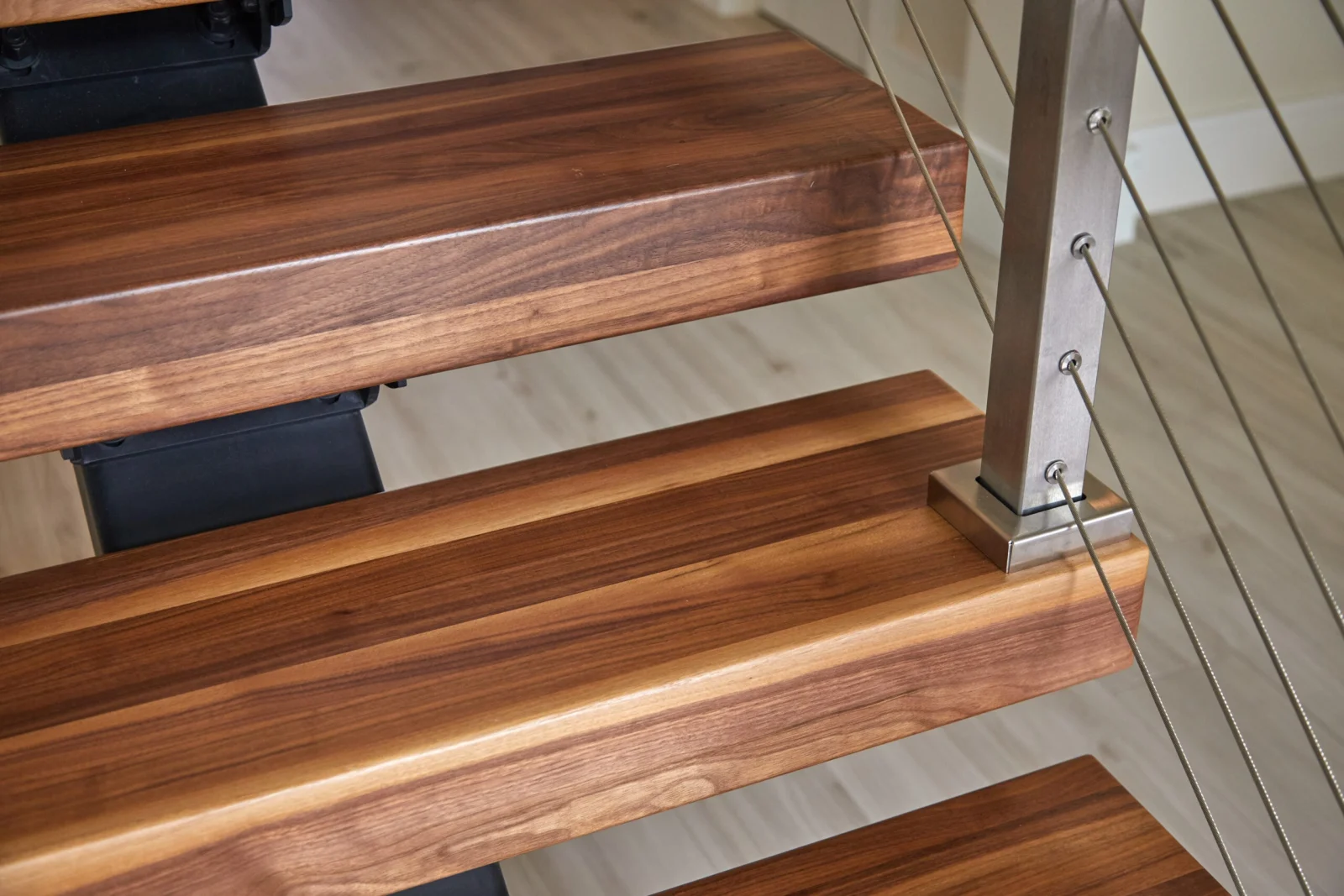 Close view of thick wood treads with a stainless post and cables