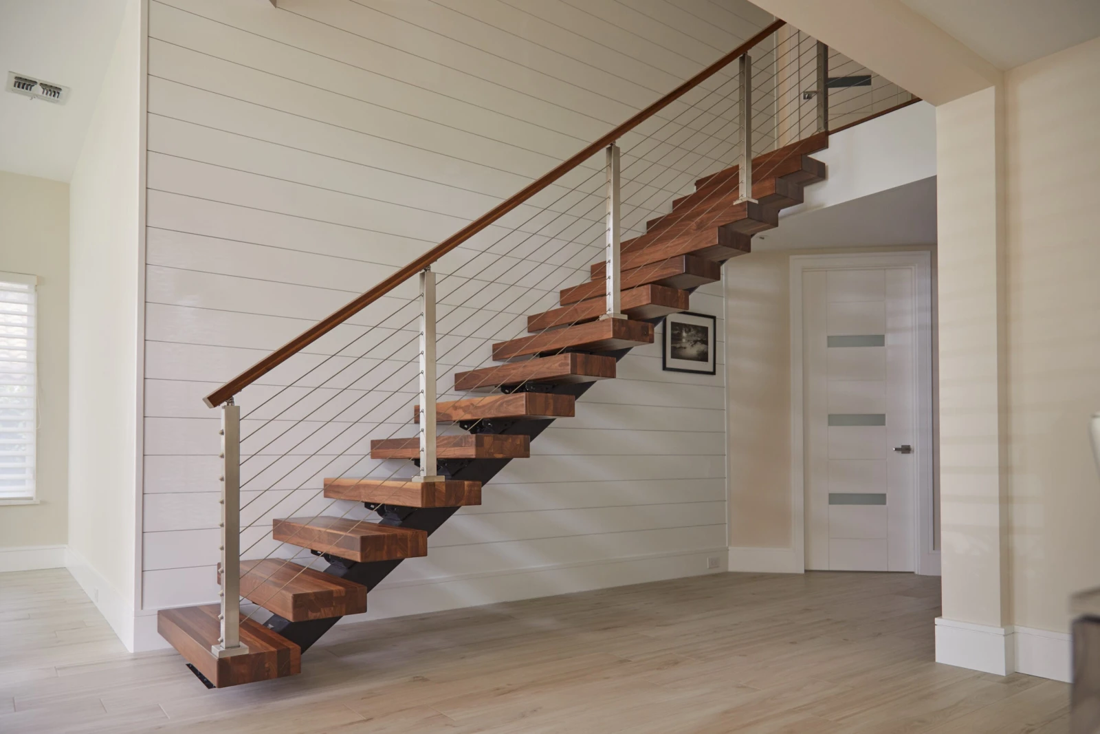 Full straight flight of wood treads on a black stringer against shiplap