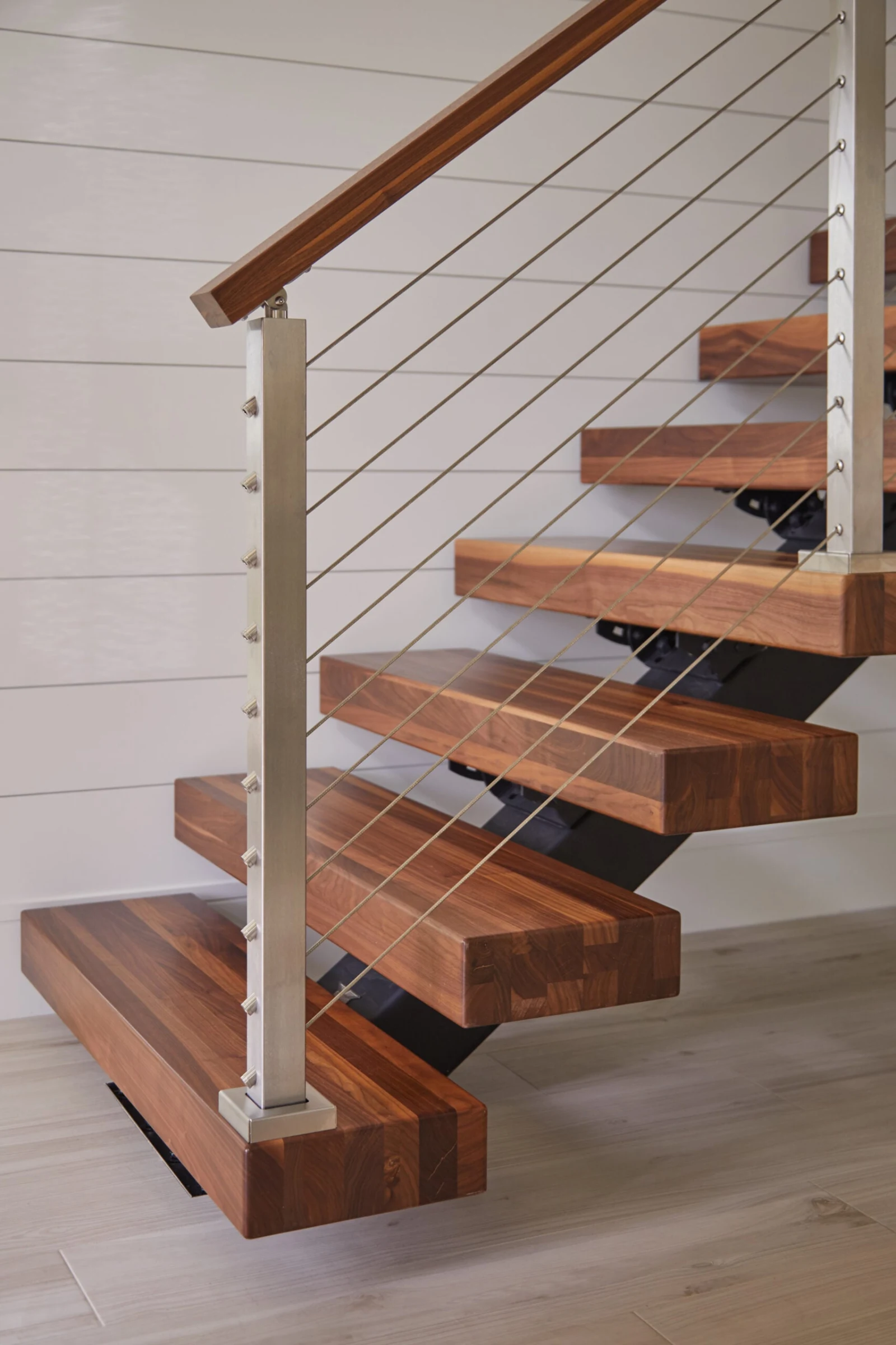 Lower treads winding up from the floor beside a stainless cable railing