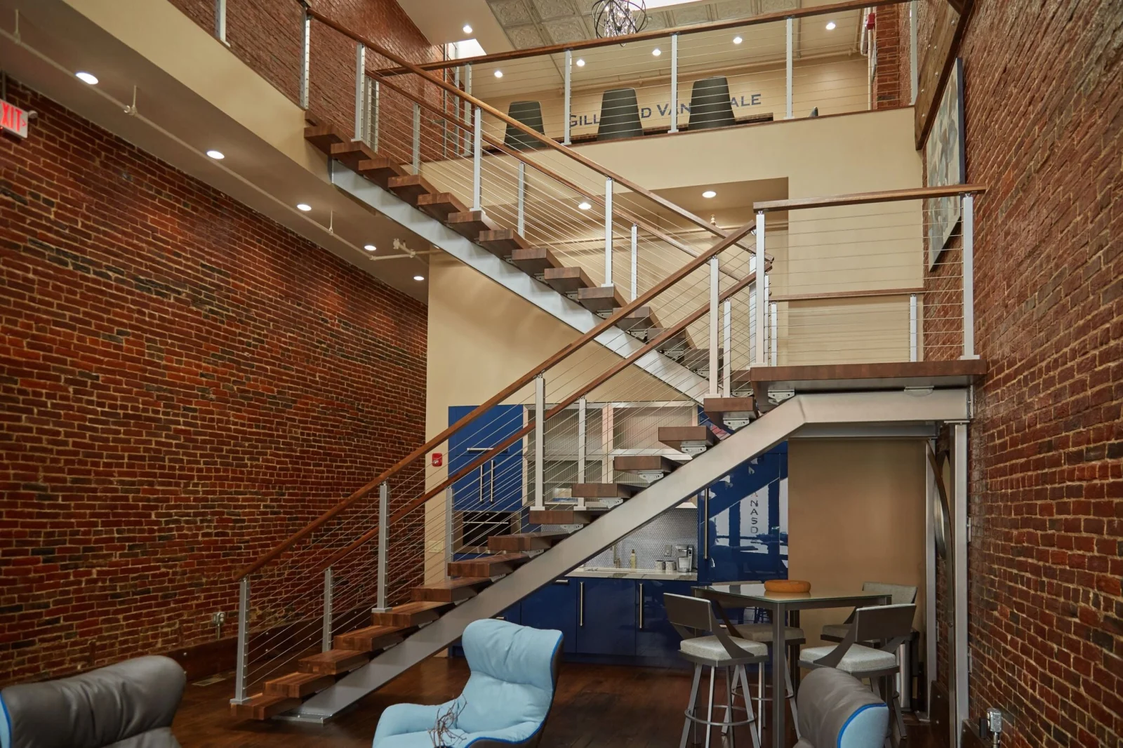 Long stair run with cable railing spanning a double-height brick interior