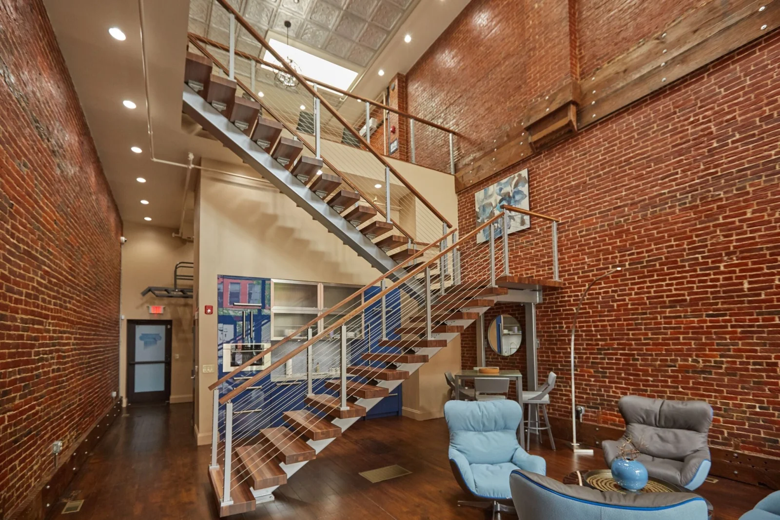 Stair and mezzanine railing in a tall brick room with lounge seating