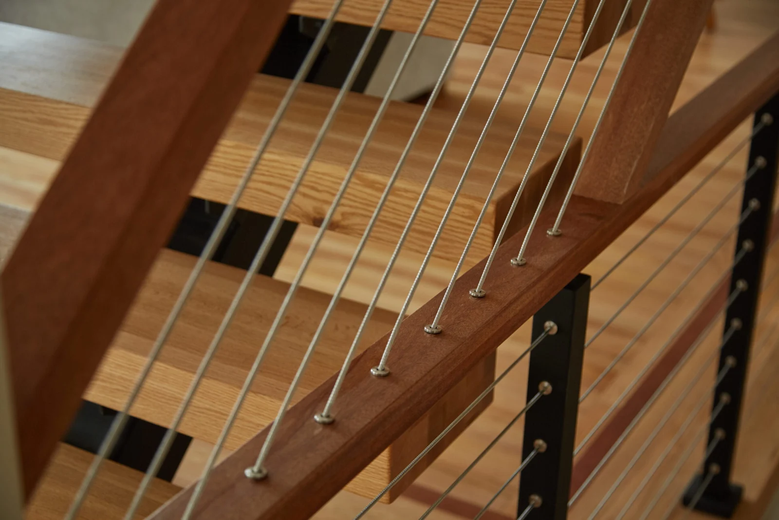 Close view of cable terminations through a wood top rail above open treads