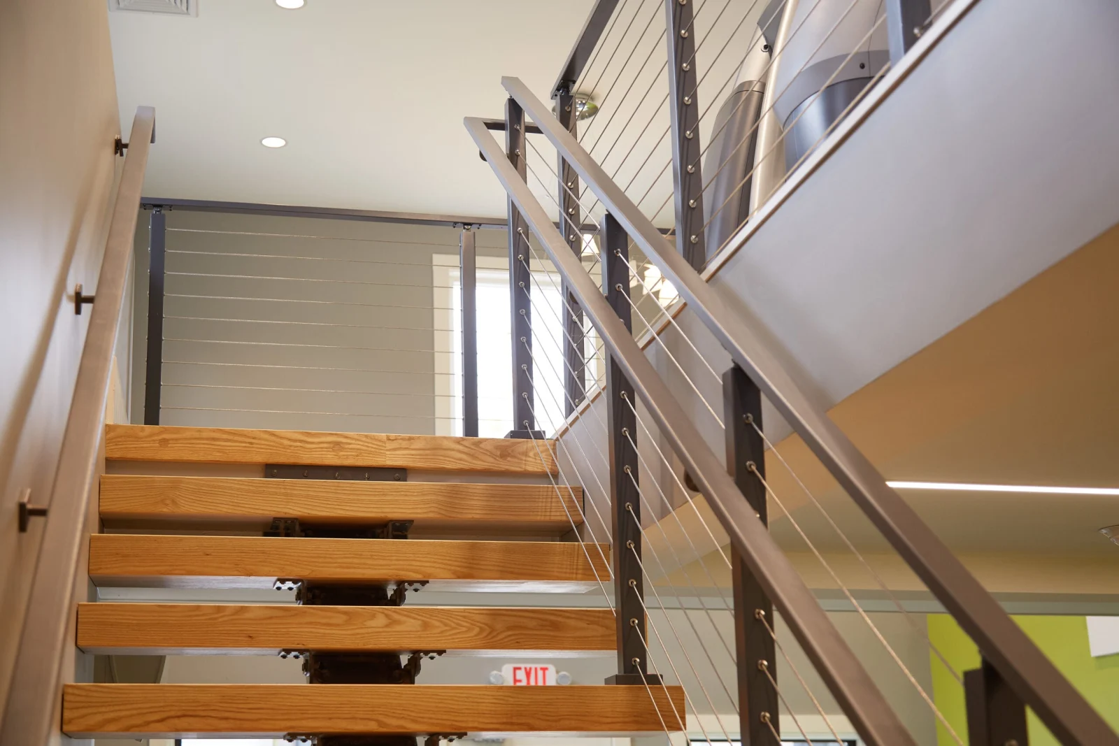 Looking up the stair toward the mezzanine railing and cardio machines