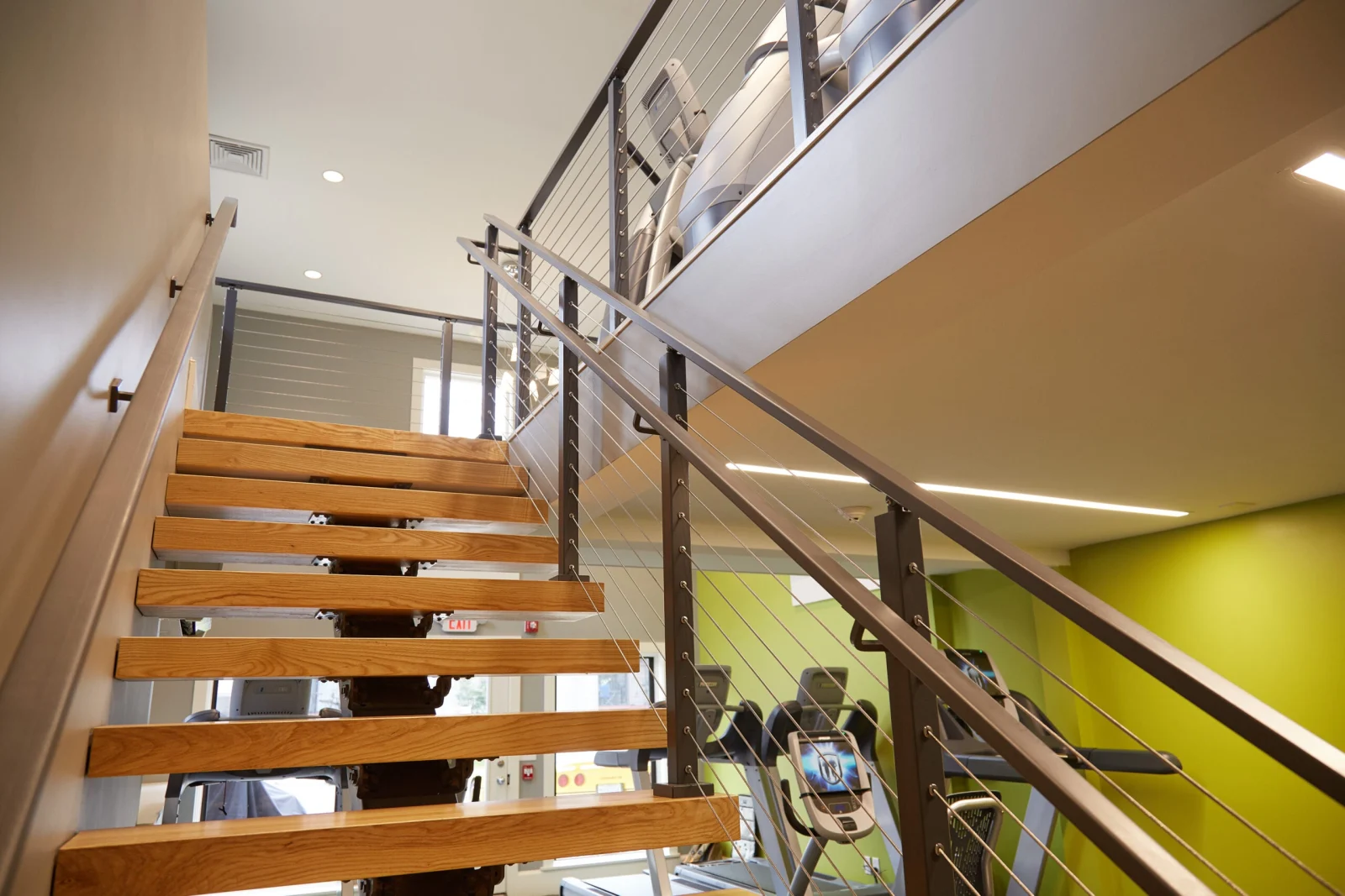 View up the flight past open treads toward the upper gym floor