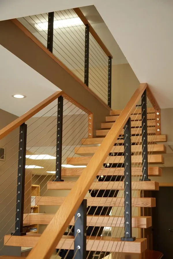 Switchback flights with cable railing rising toward an upper office landing
