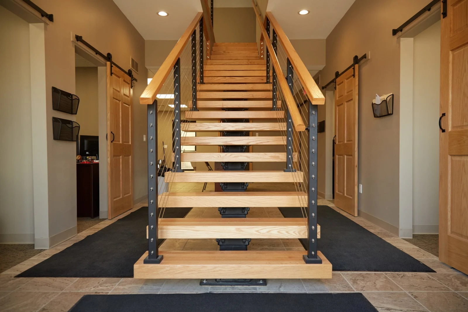 Floating stair centered in a tiled entry between two sliding barn doors