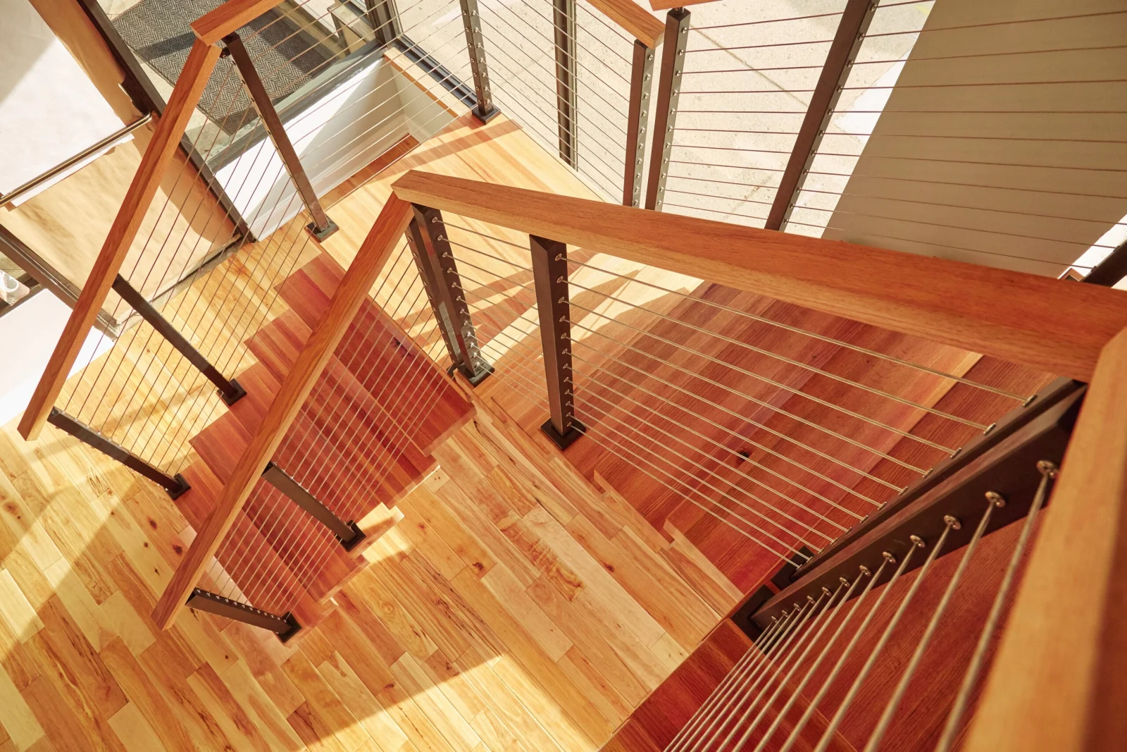 Looking down into the stairwell at cable railing wrapping the U-shaped turn
