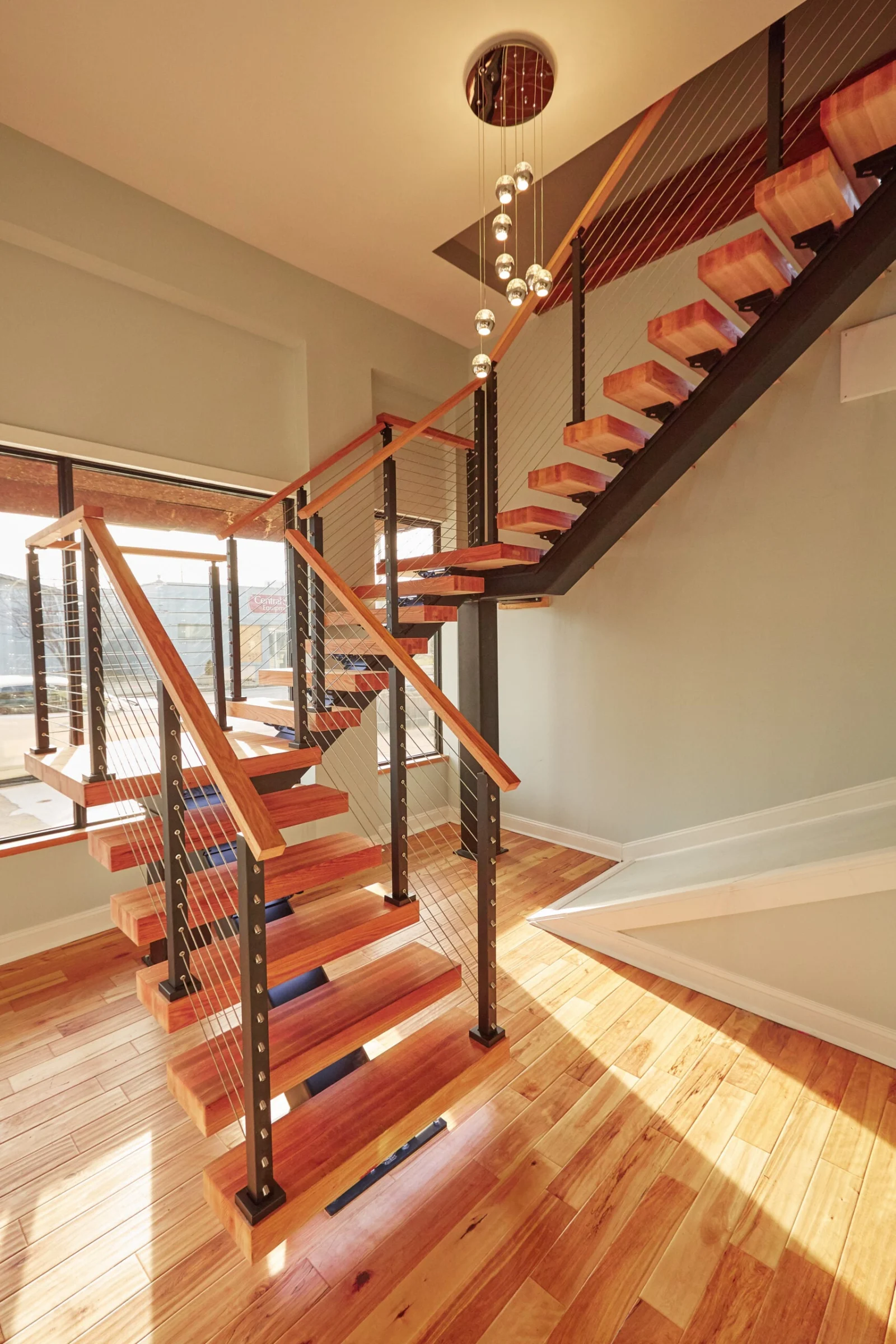 U-shaped floating stair turning at a landing beside tall entry windows