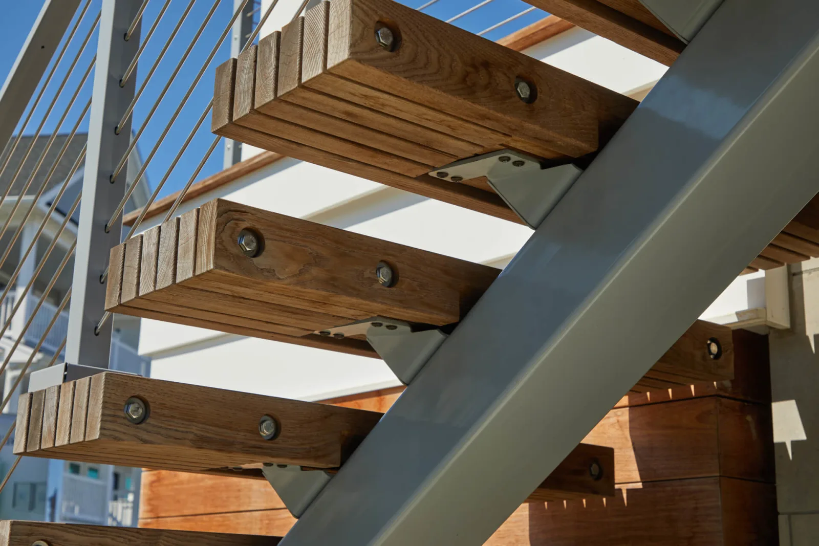 Underside view of slatted treads bolted to a gray steel mono stringer