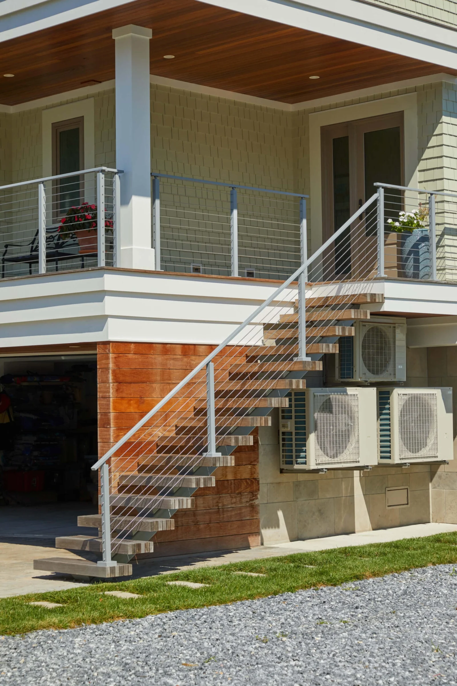 Outdoor floating stair with rod railing descending from a covered porch