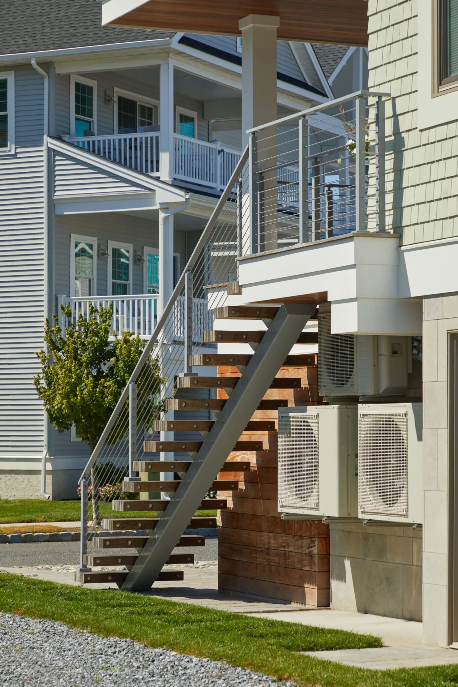 Stainless rod railing along stairs rising to a second-level deck