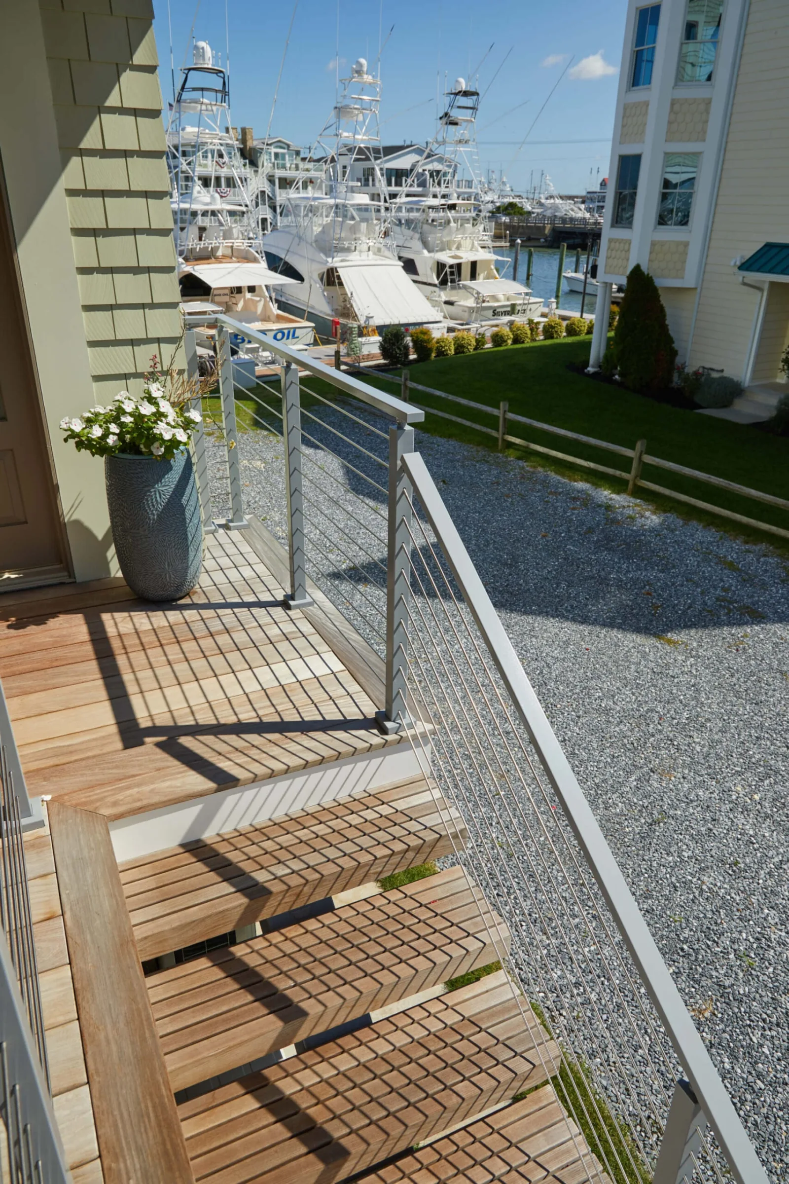 Rod railing beside slatted outdoor treads leading down to a gravel yard