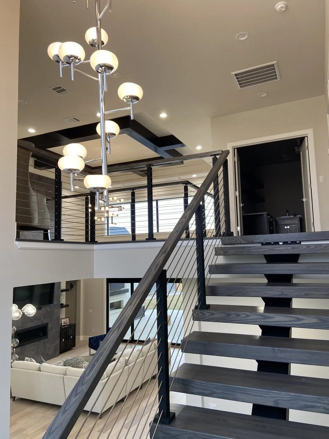 View up the flight past a chandelier toward the railed loft above