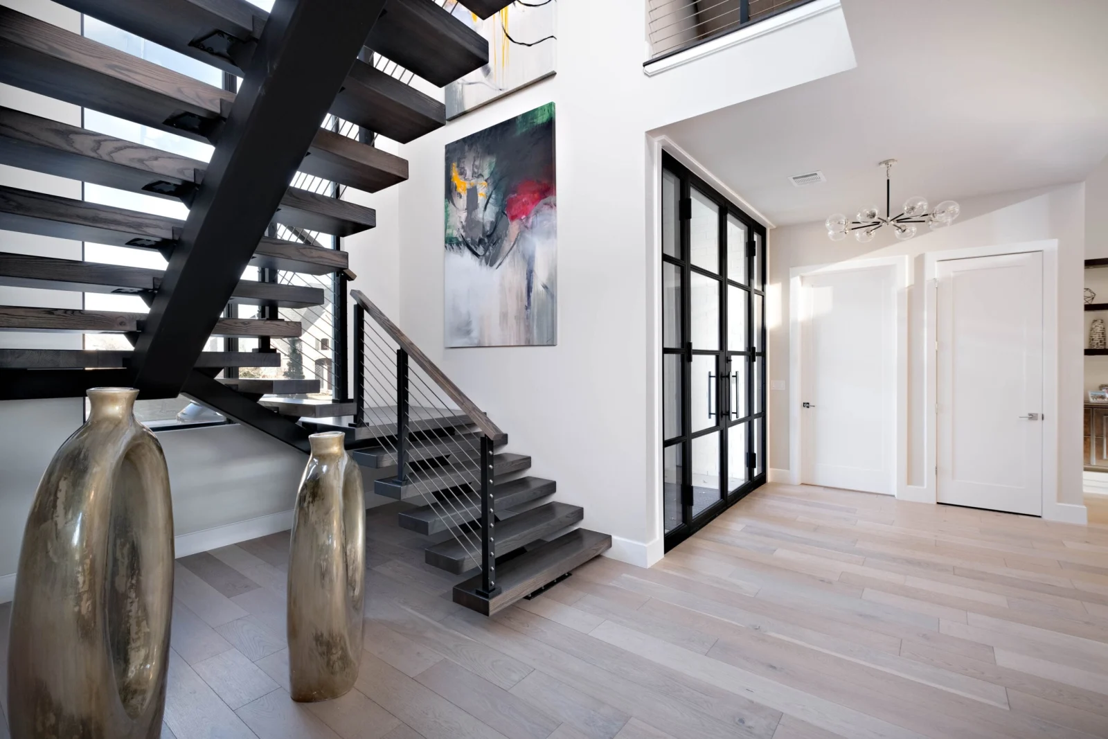 Entry view of the floating stair with gray treads and black rod railing