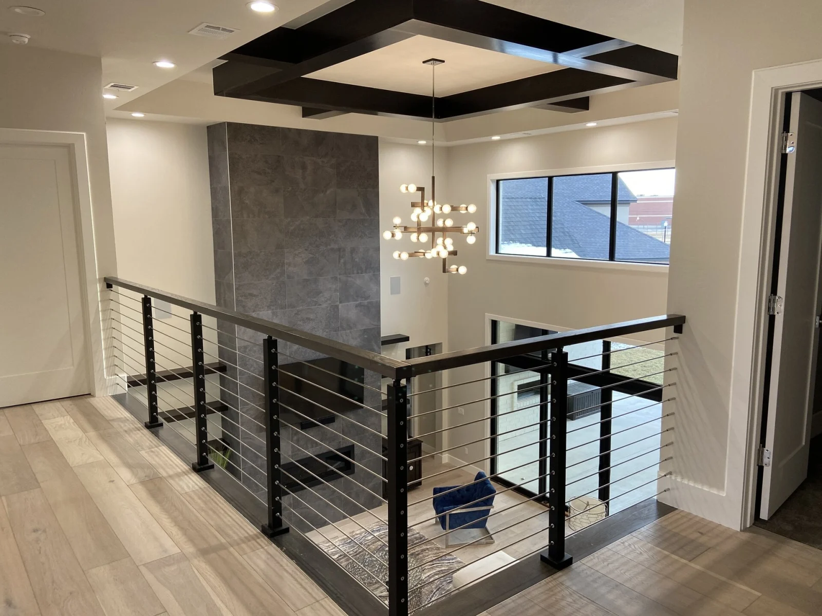 Upstairs overlook where the rod railing wraps the opening under a beamed ceiling