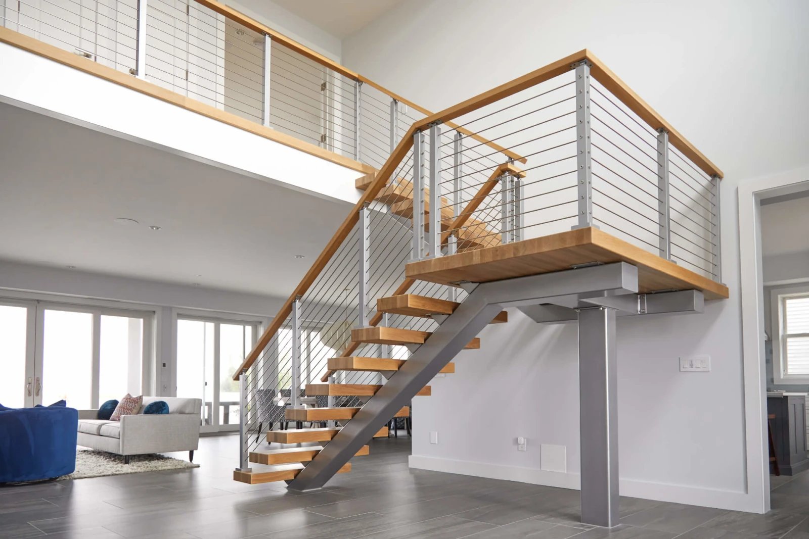 Silver posts and stainless rods carry a wood top rail beside the landing