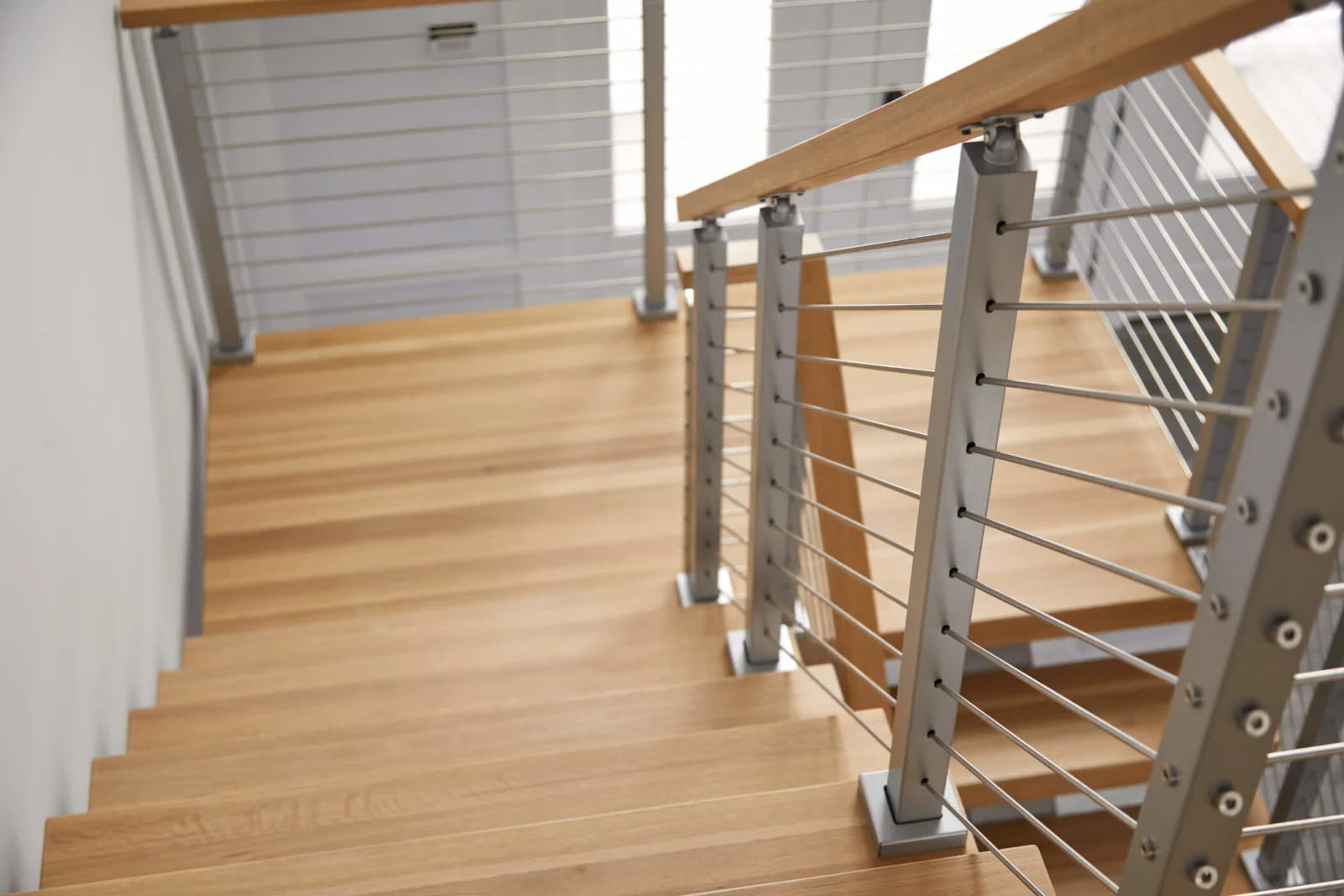 Looking down the wood treads toward a landing with rod railing at right