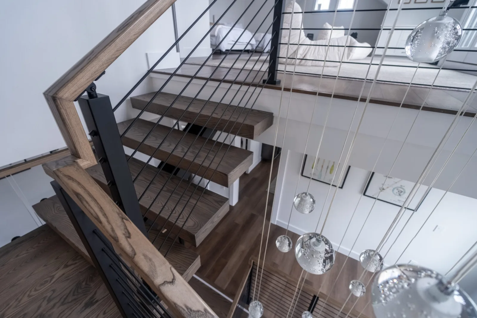 View down the treads from the upper level past a cluster of glass pendants