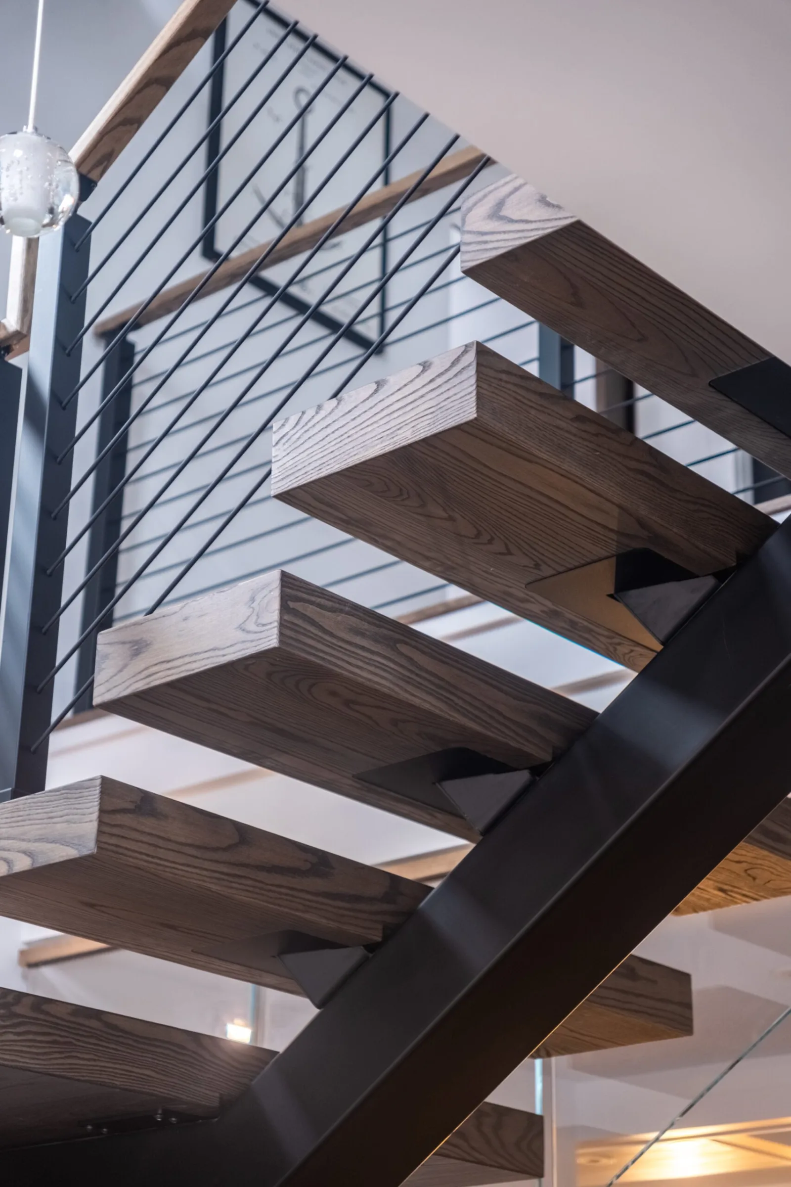 Looking up at gray-brown treads cantilevered from the black stringer