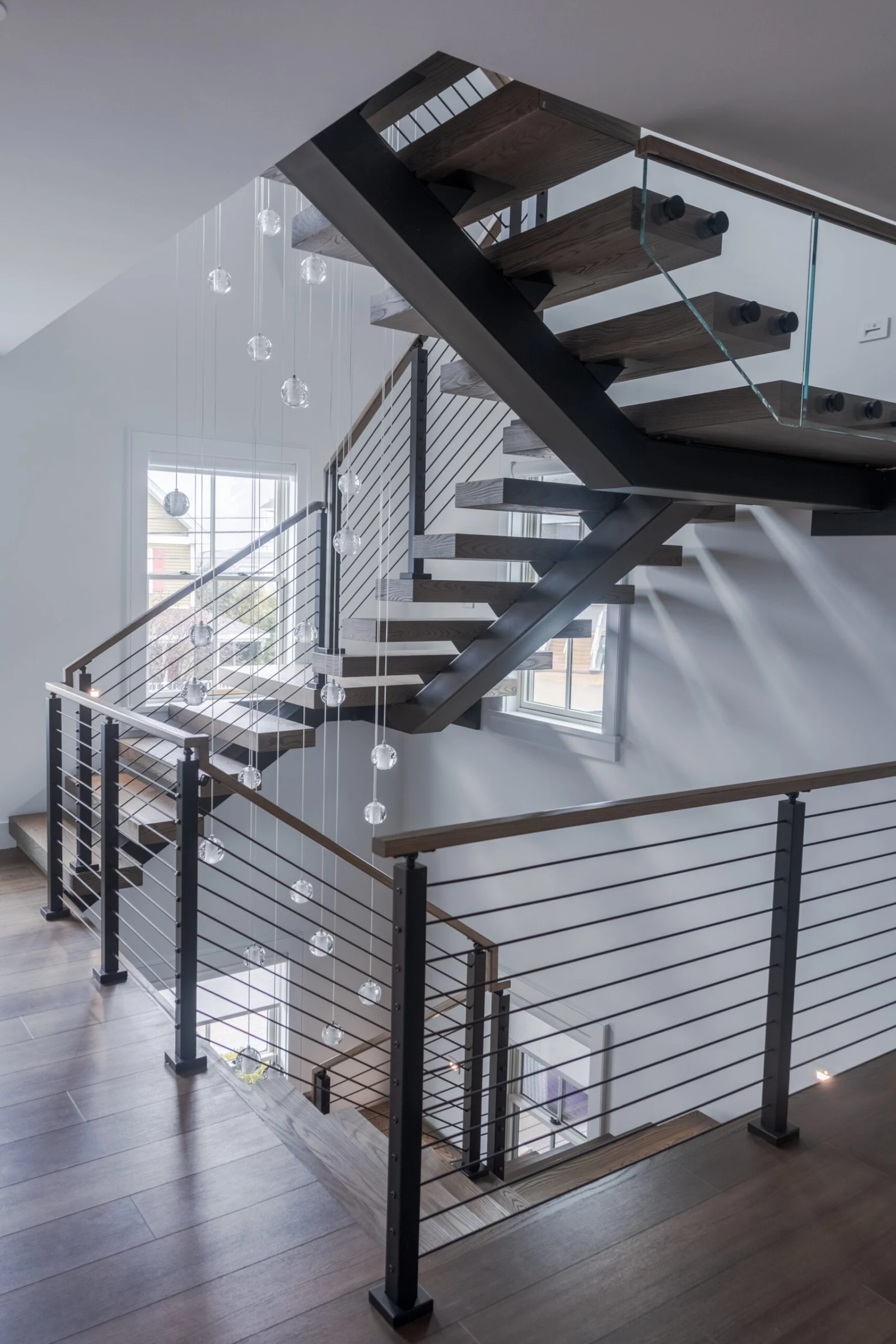 Aerial view of a switchback stair with cable railing and a glass panel at the landing