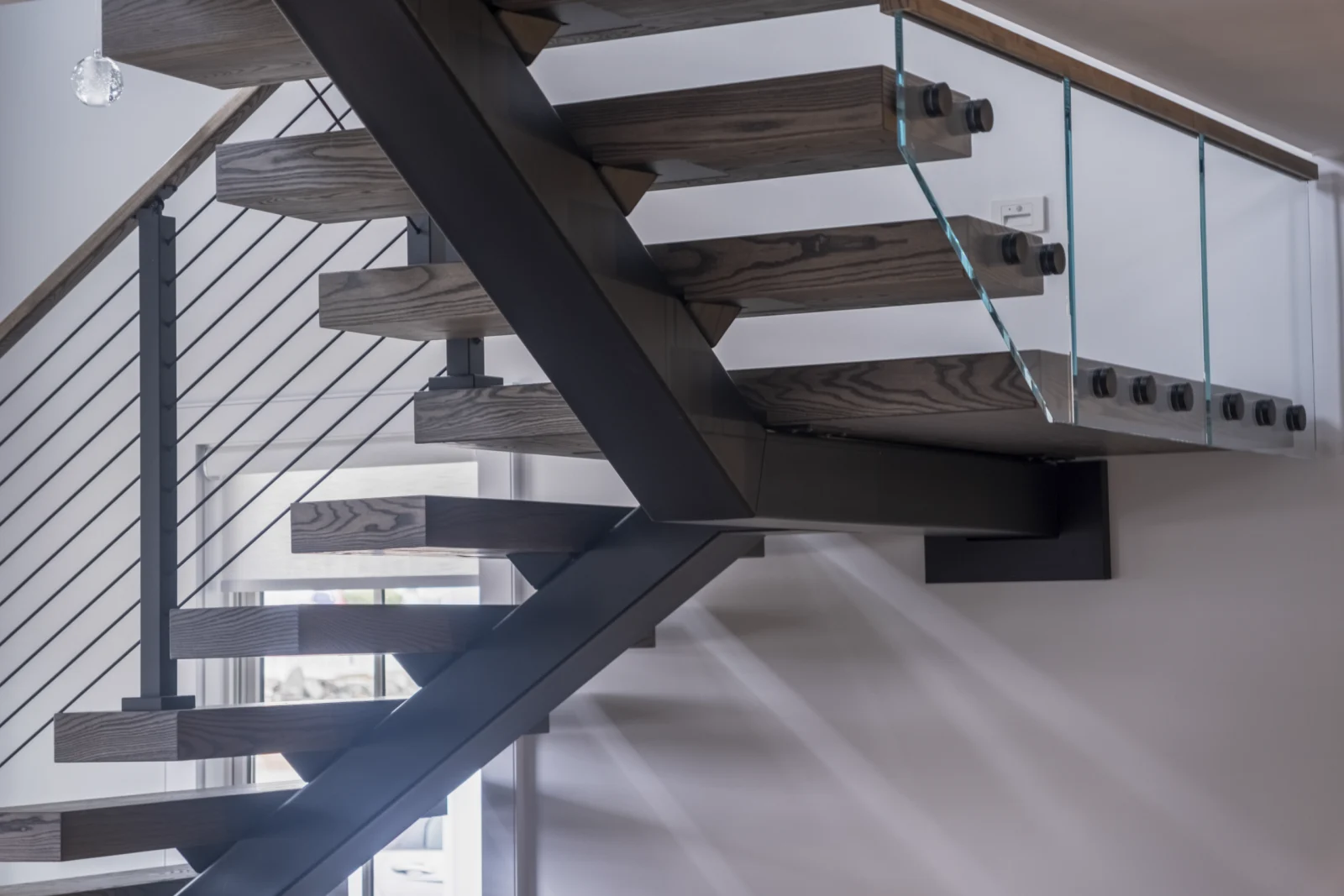 Underside detail where treads meet the stringer beside a glass railing panel