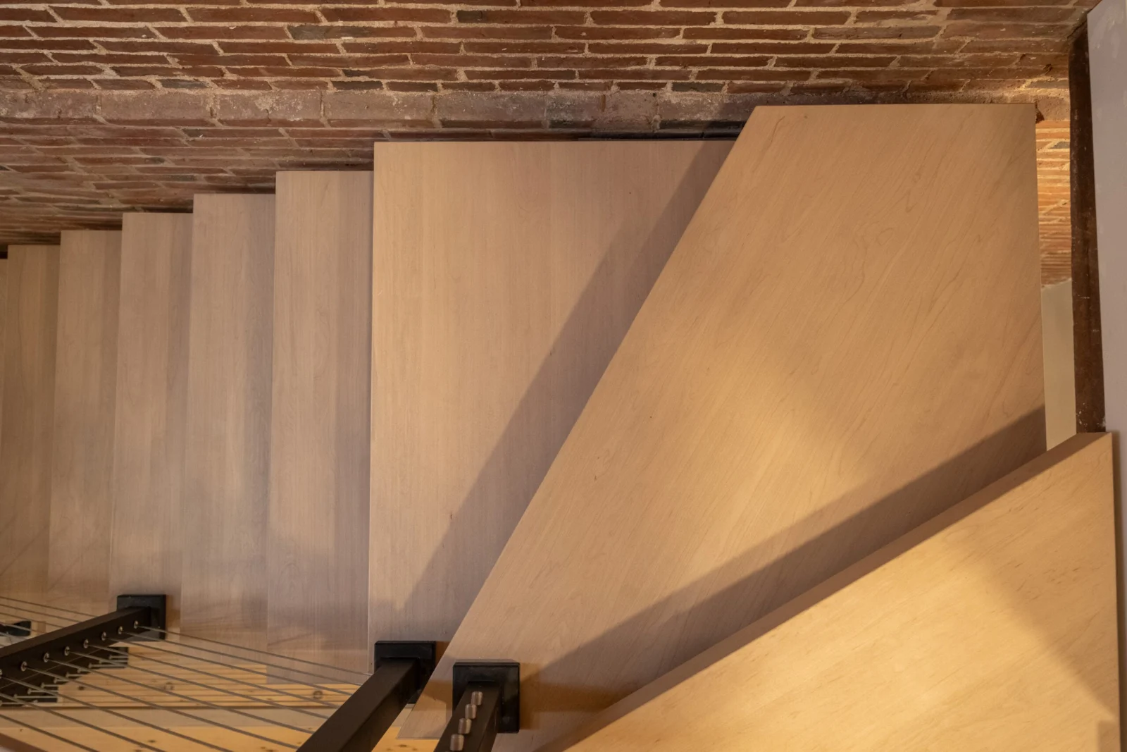 Light wood treads viewed from below against the brick ceiling line