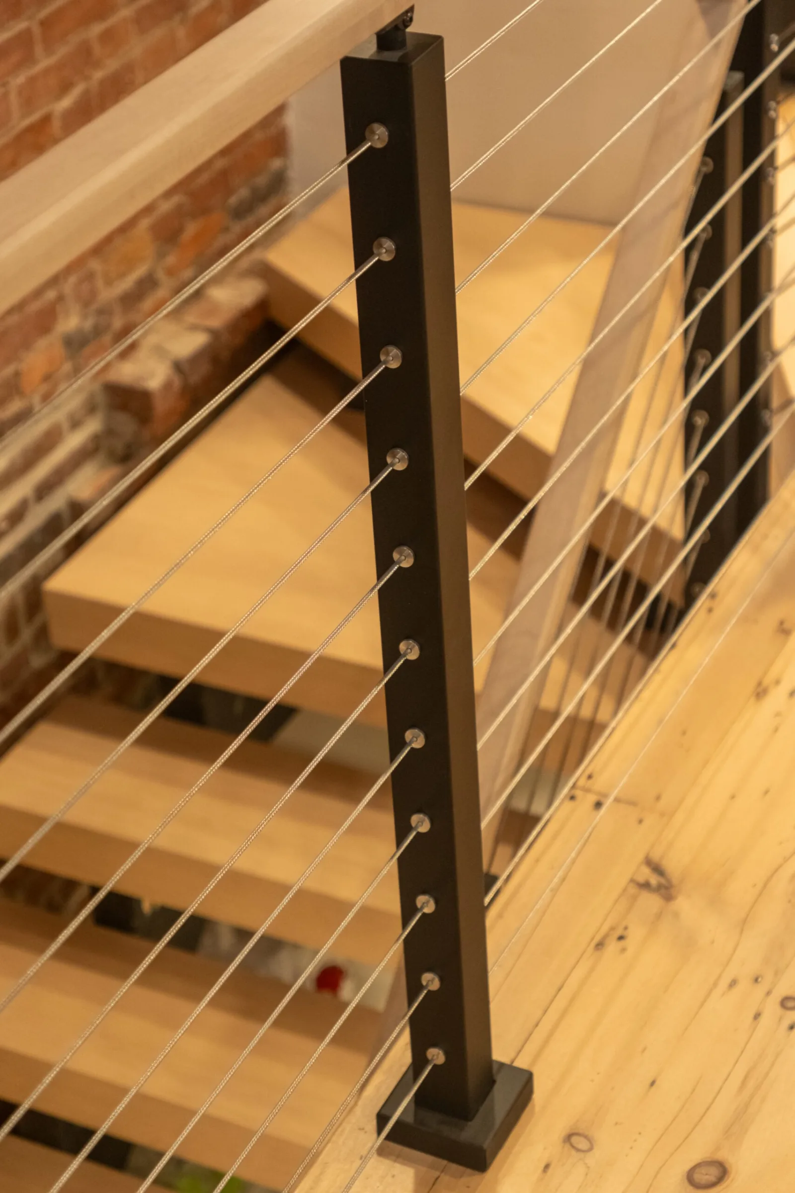 Close view of a black cable railing post with swaged fittings