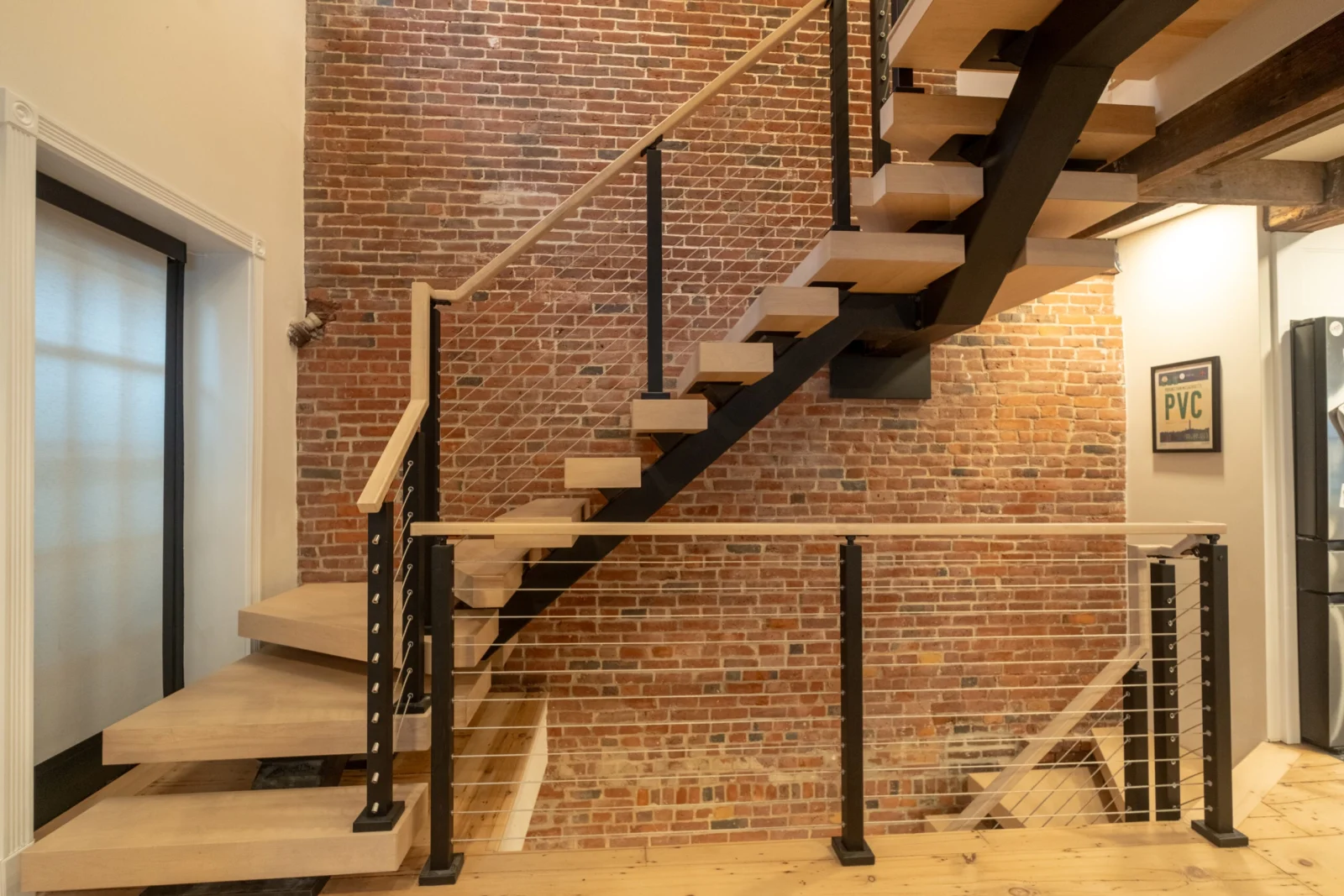 Full flight against the brick wall with cable railing and wide-plank floor