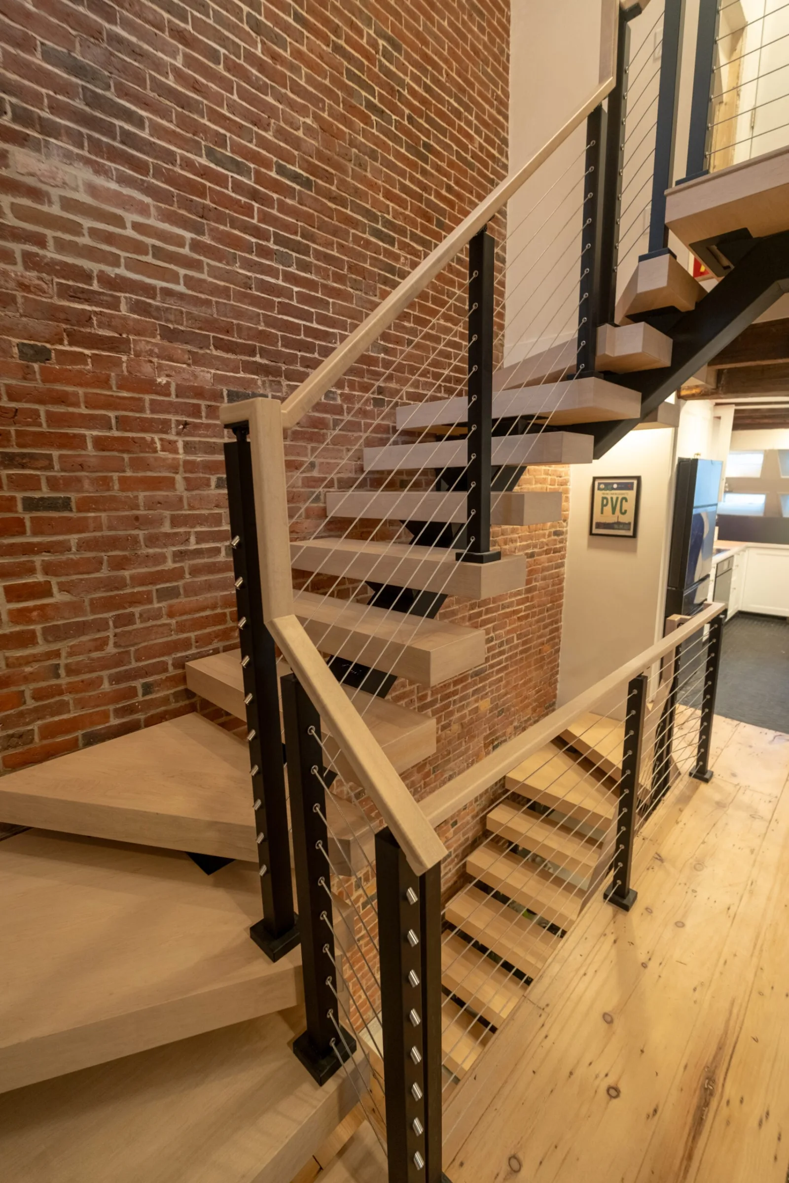 Winder treads turning at the base with cable railing and brick behind