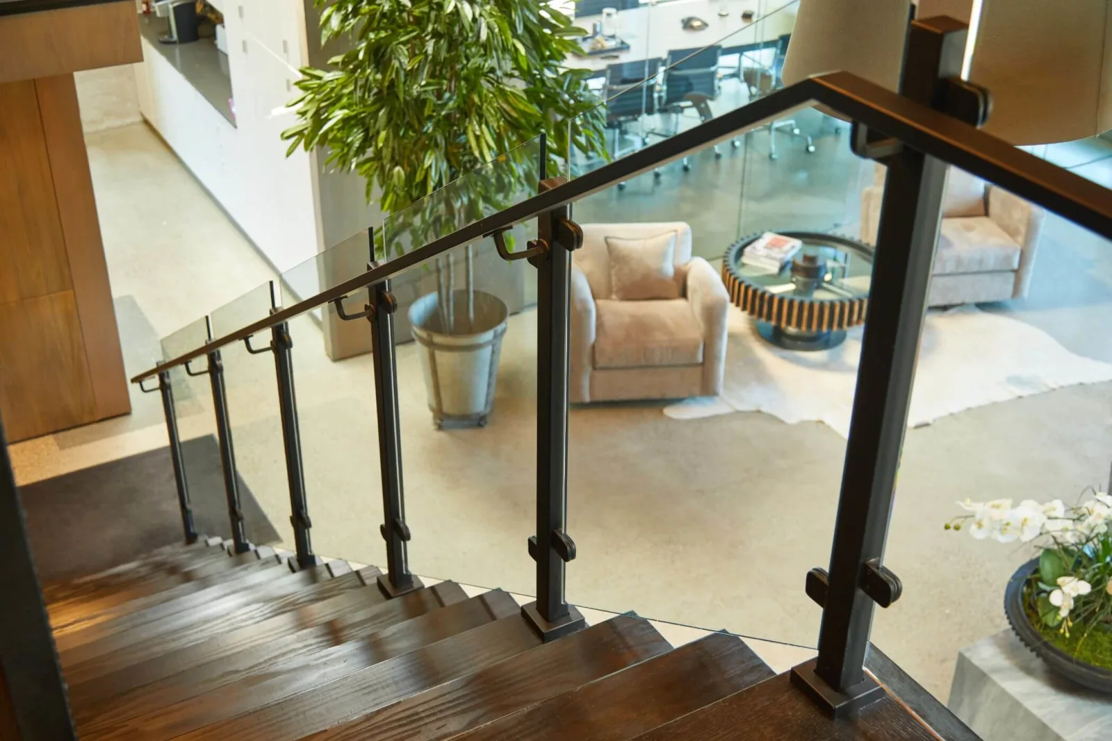 Looking down dark treads with glass railing posts mounted to the treads