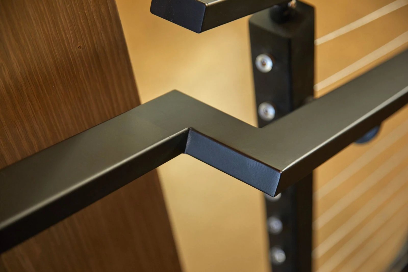 Mitered corner of a dark metal top rail at a post