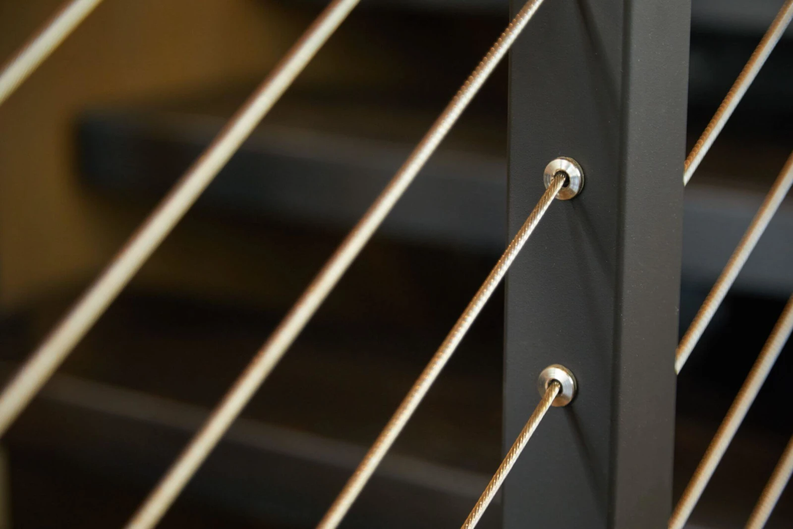 Macro of cable passing through a black post with beveled washers