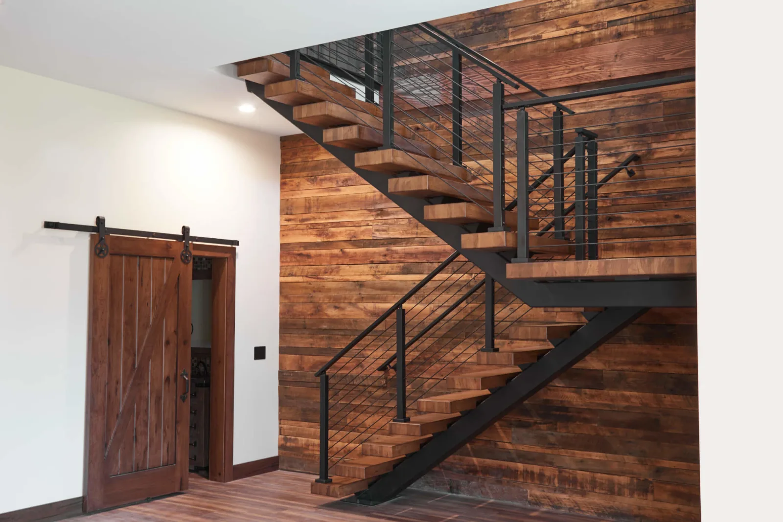Switchback flight on a reclaimed wood wall beside a sliding barn door
