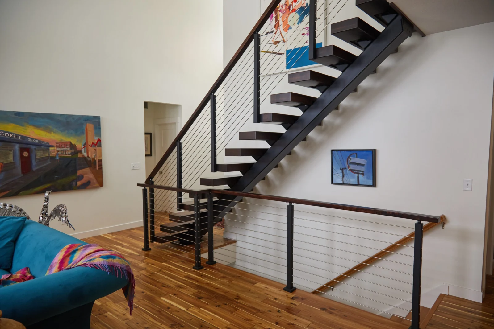 Living room with the stair, rod railing overlook and framed artwork