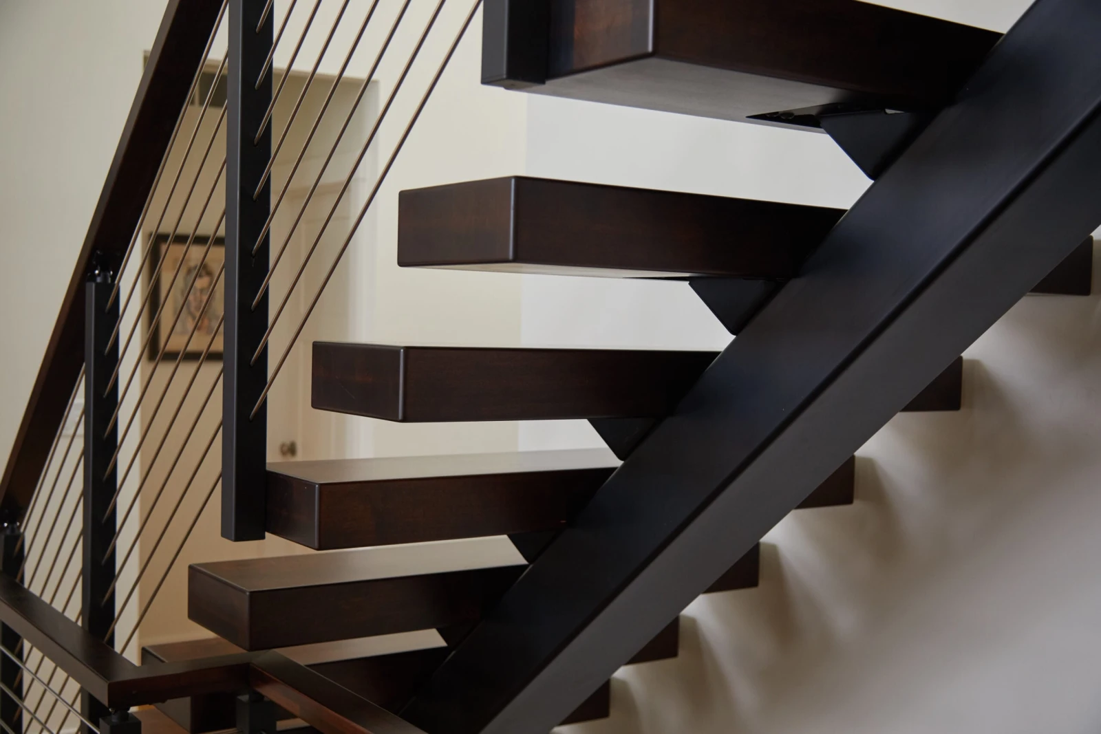 Side view of dark cantilevered treads springing from the black stringer