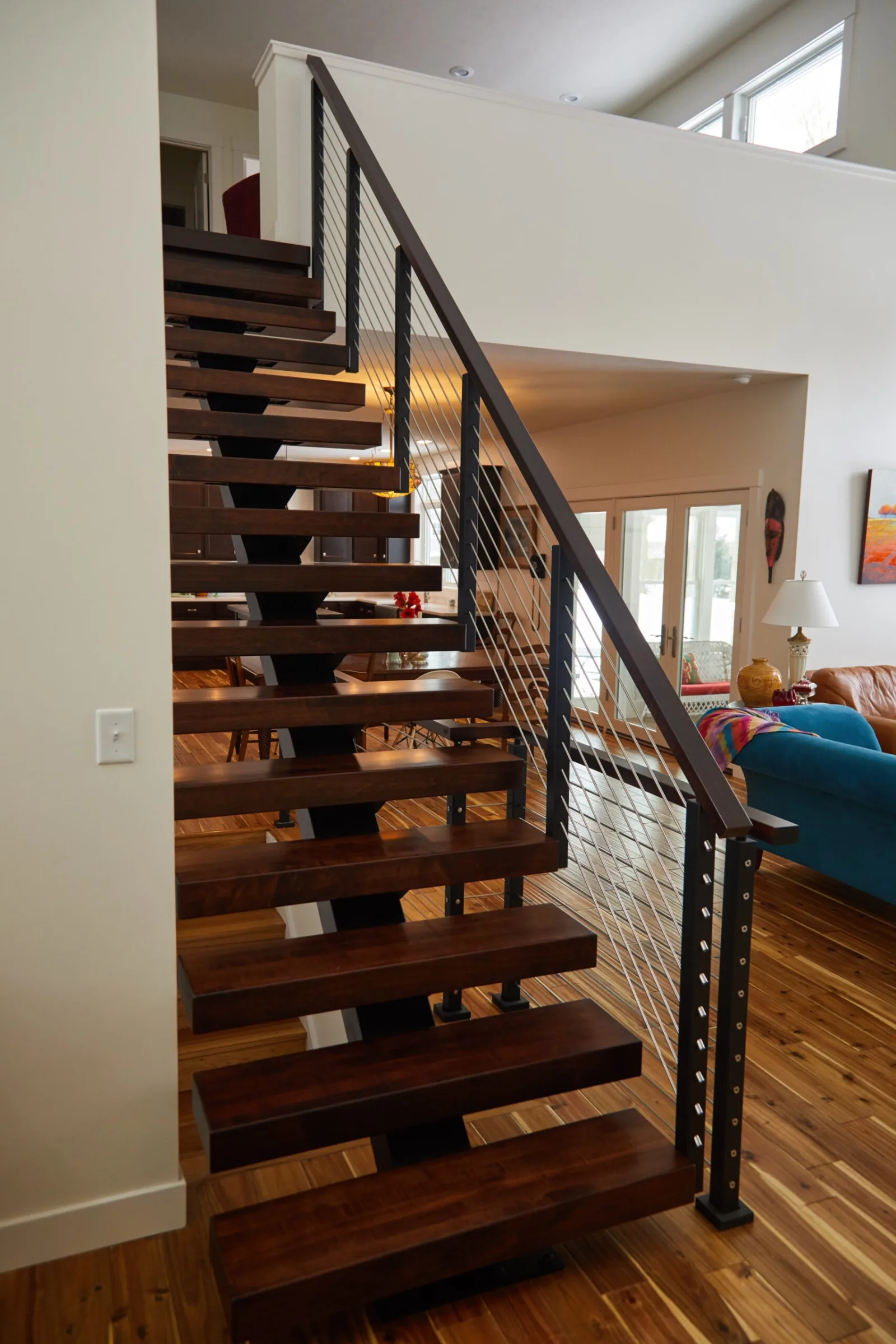Straight flight of dark treads with rod railing and wood top rail
