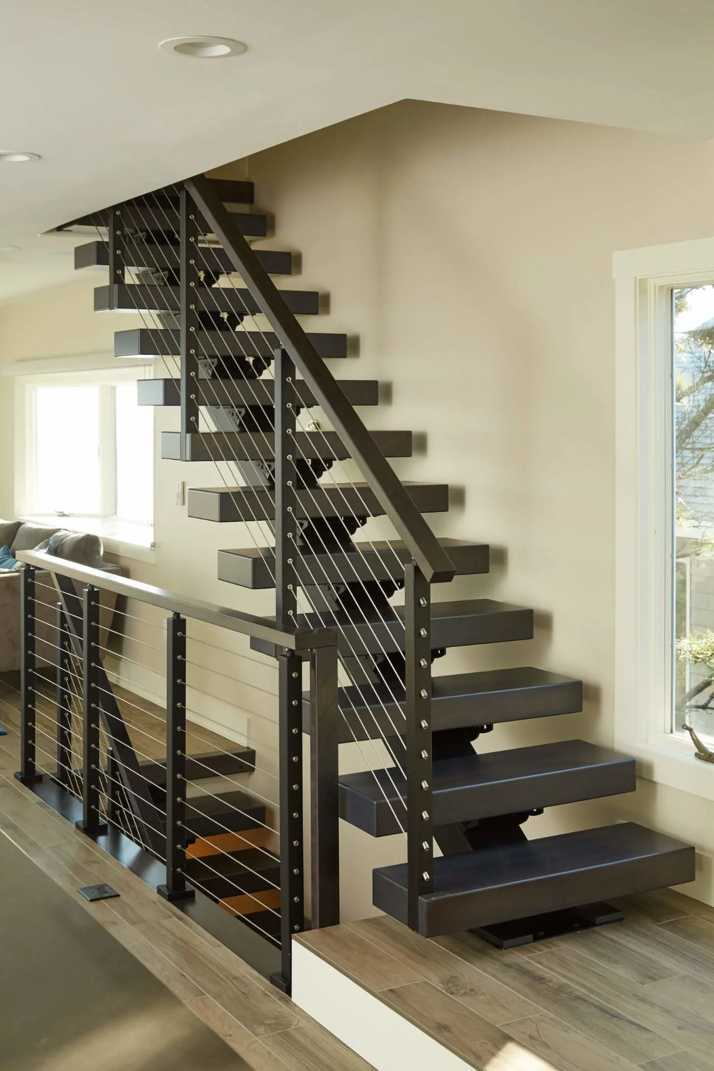 Full flight of dark treads with cable railing and landing run