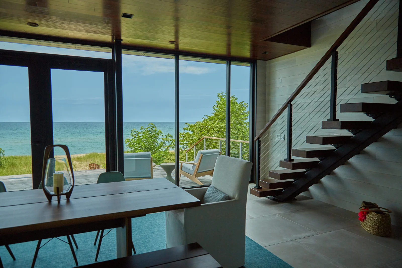 Dining table by a glass wall with the stair and lake beyond
