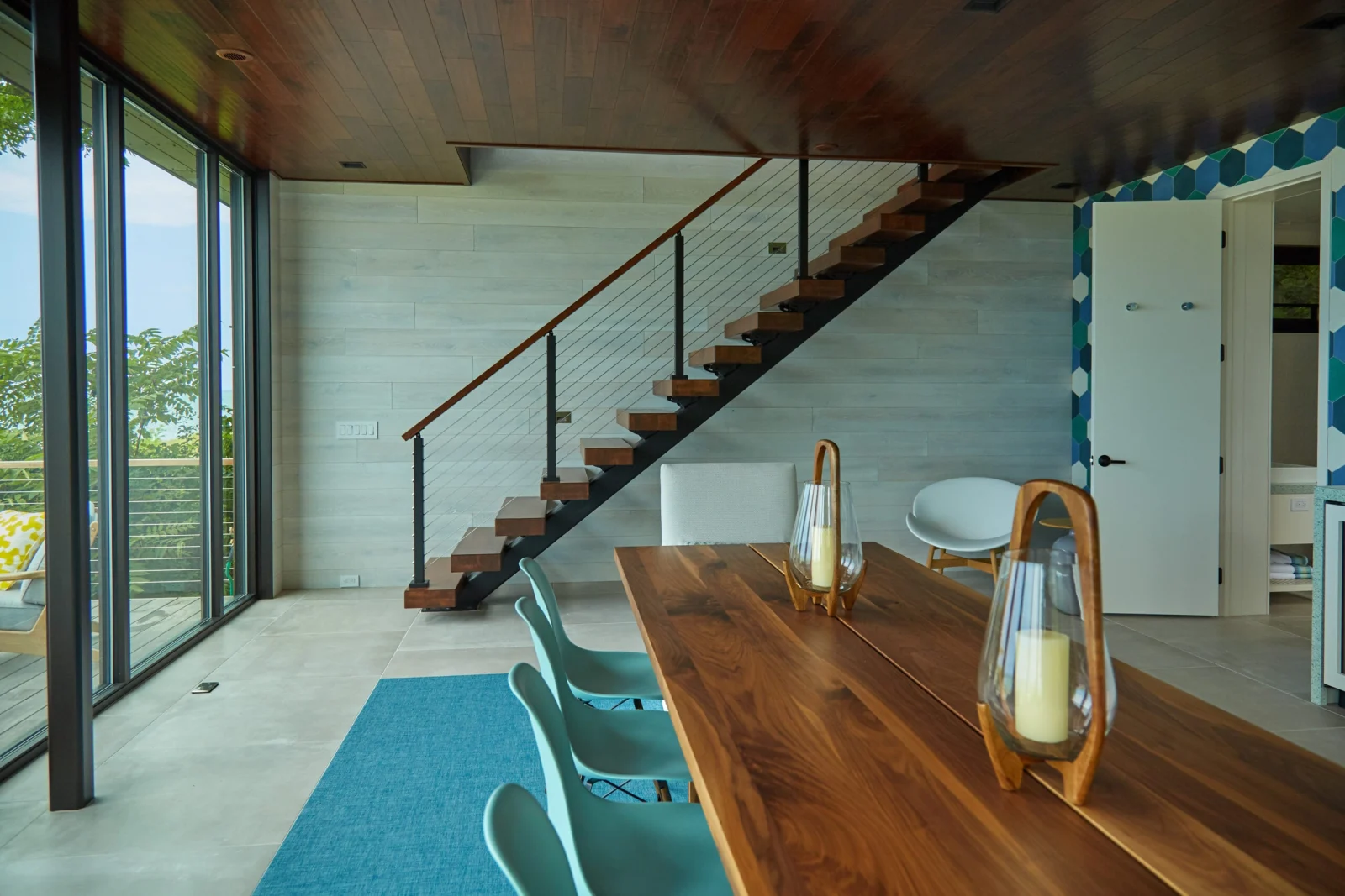 Stair along a white plank wall with cable railing and wood top rail
