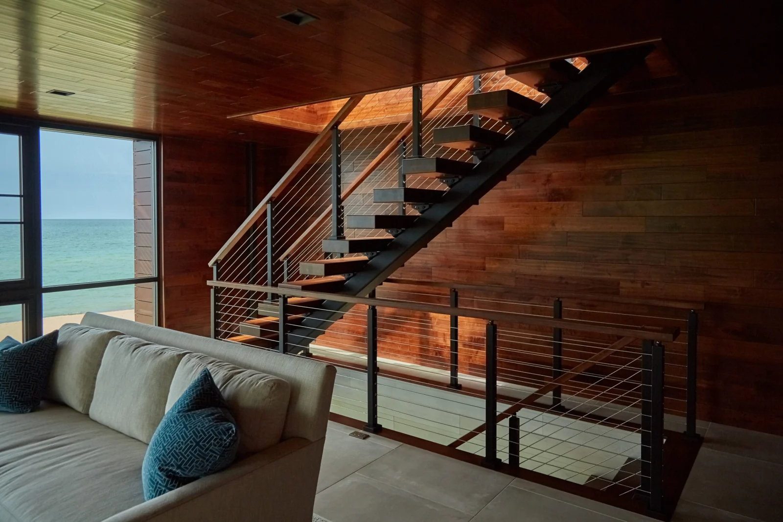 Living room under a wood ceiling with the stair and lake view