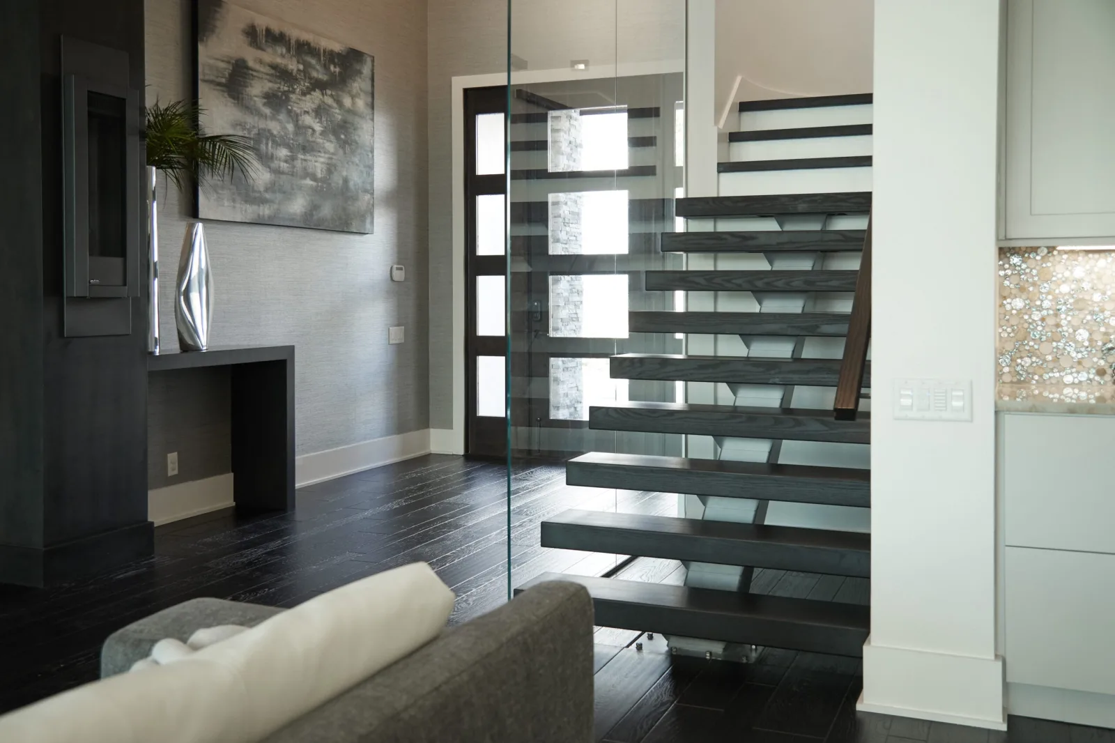 Floating stair seen through a full-height glass wall from the living room