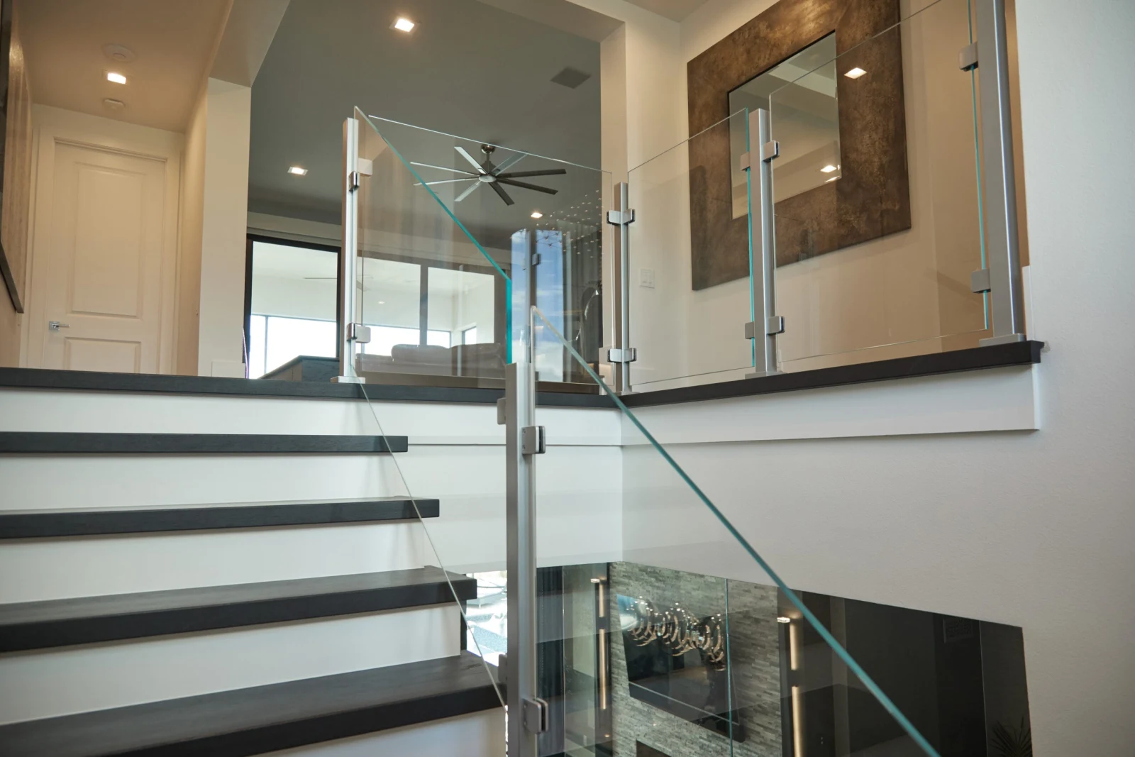 View up the stair from a landing with glass panels and dark treads