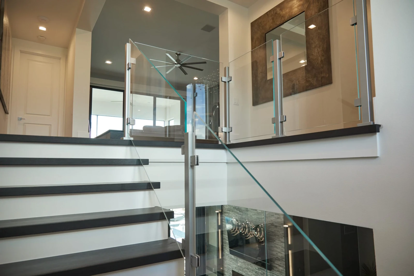 Glass railing on stainless posts guards a landing above a stone-clad lower level