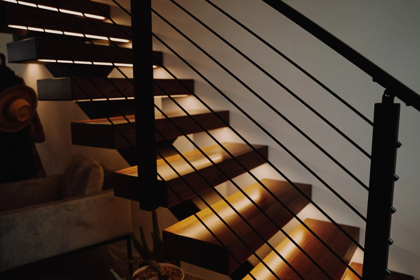 Angled view through rod infill to glowing treads carried on a single dark stringer